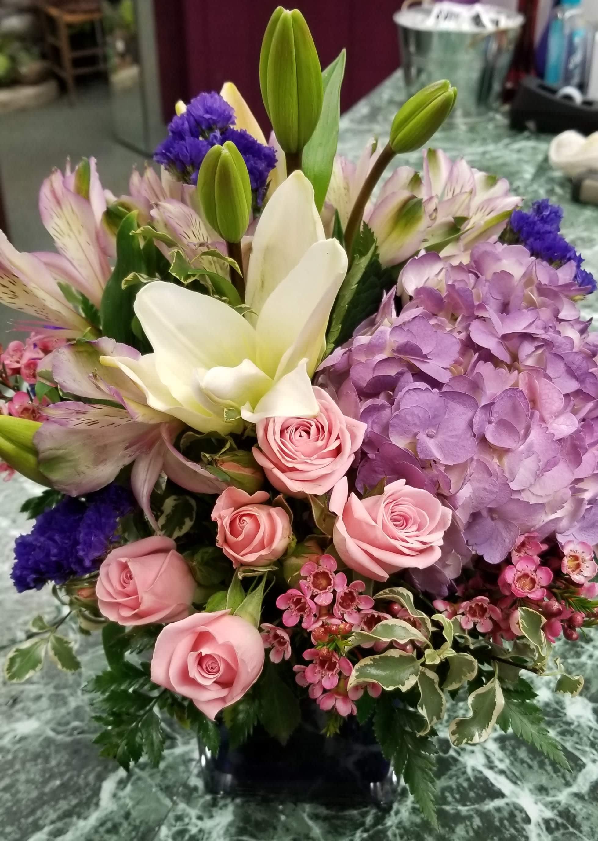 Mixed bouquet with pink roses, white lilies, and purple hydrangea in a vase