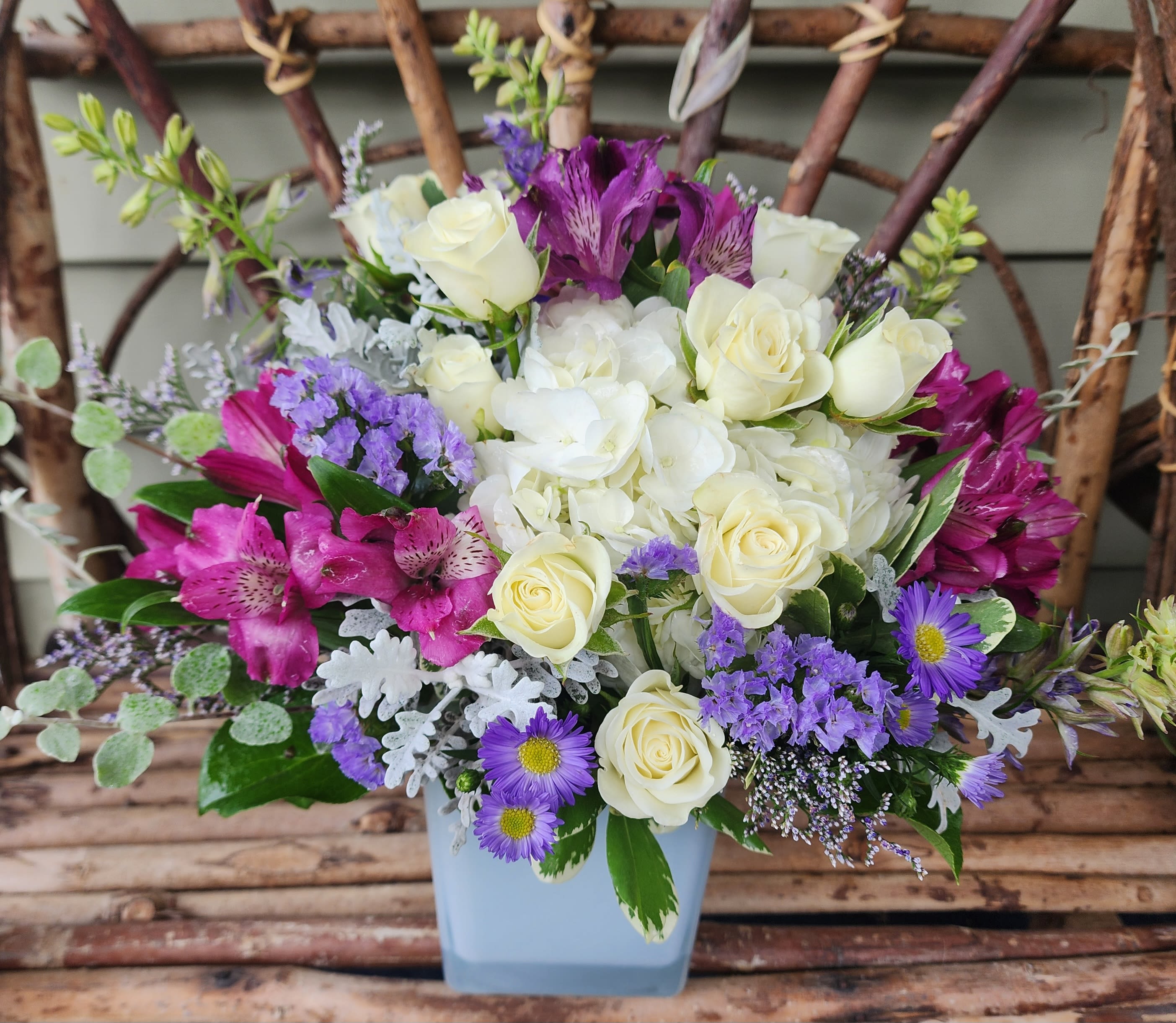 Bouquet of white and purple flowers in a light blue vase