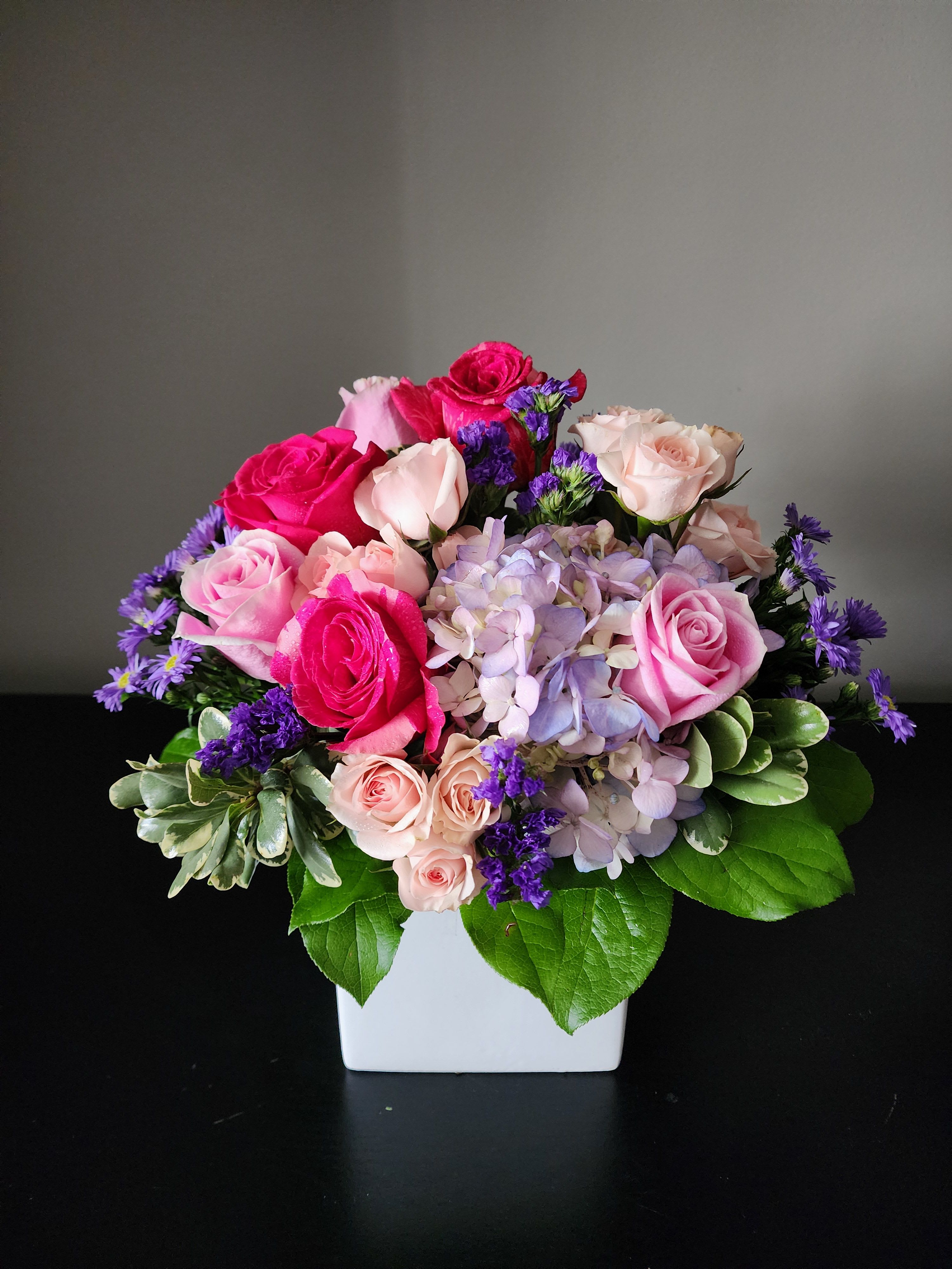 Pink and lavender rose bouquet in a white square vase