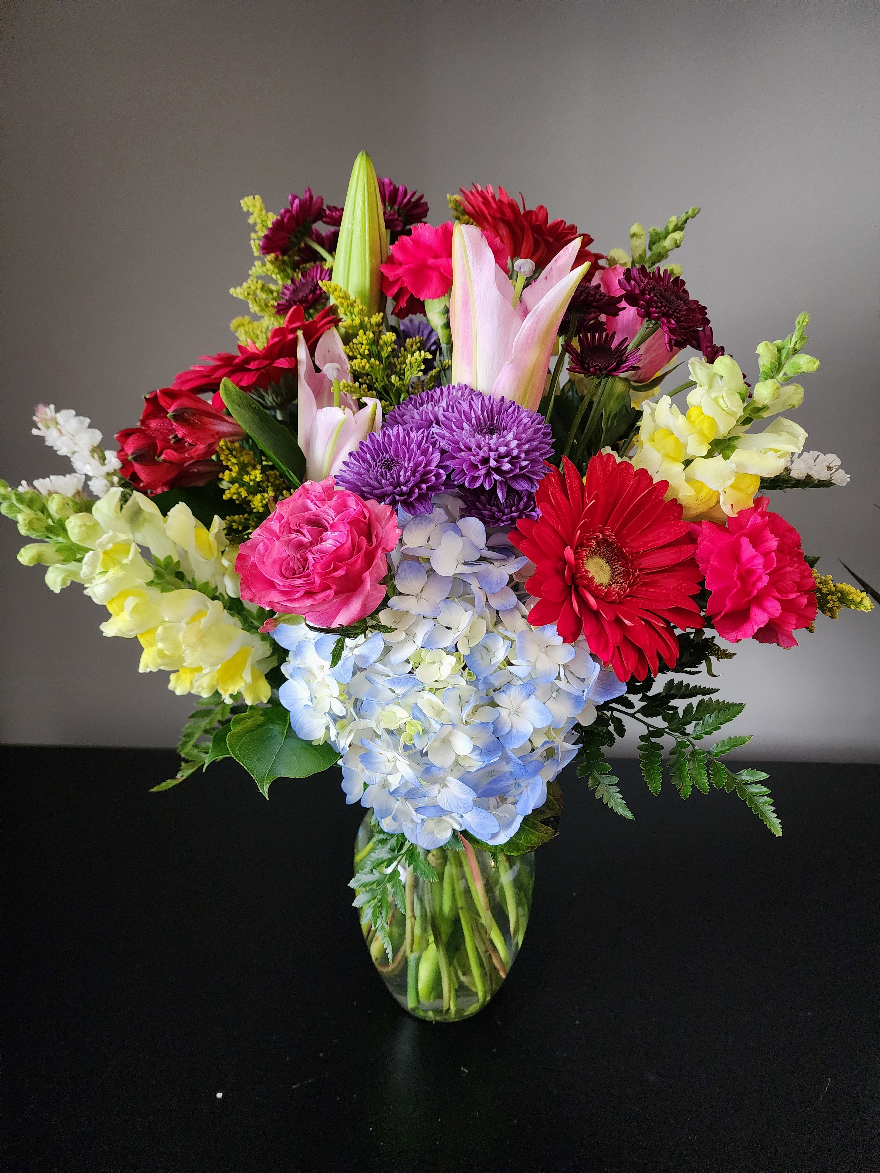 Mixed bouquet in a glass vase with pink, purple, red, and yellow flowers