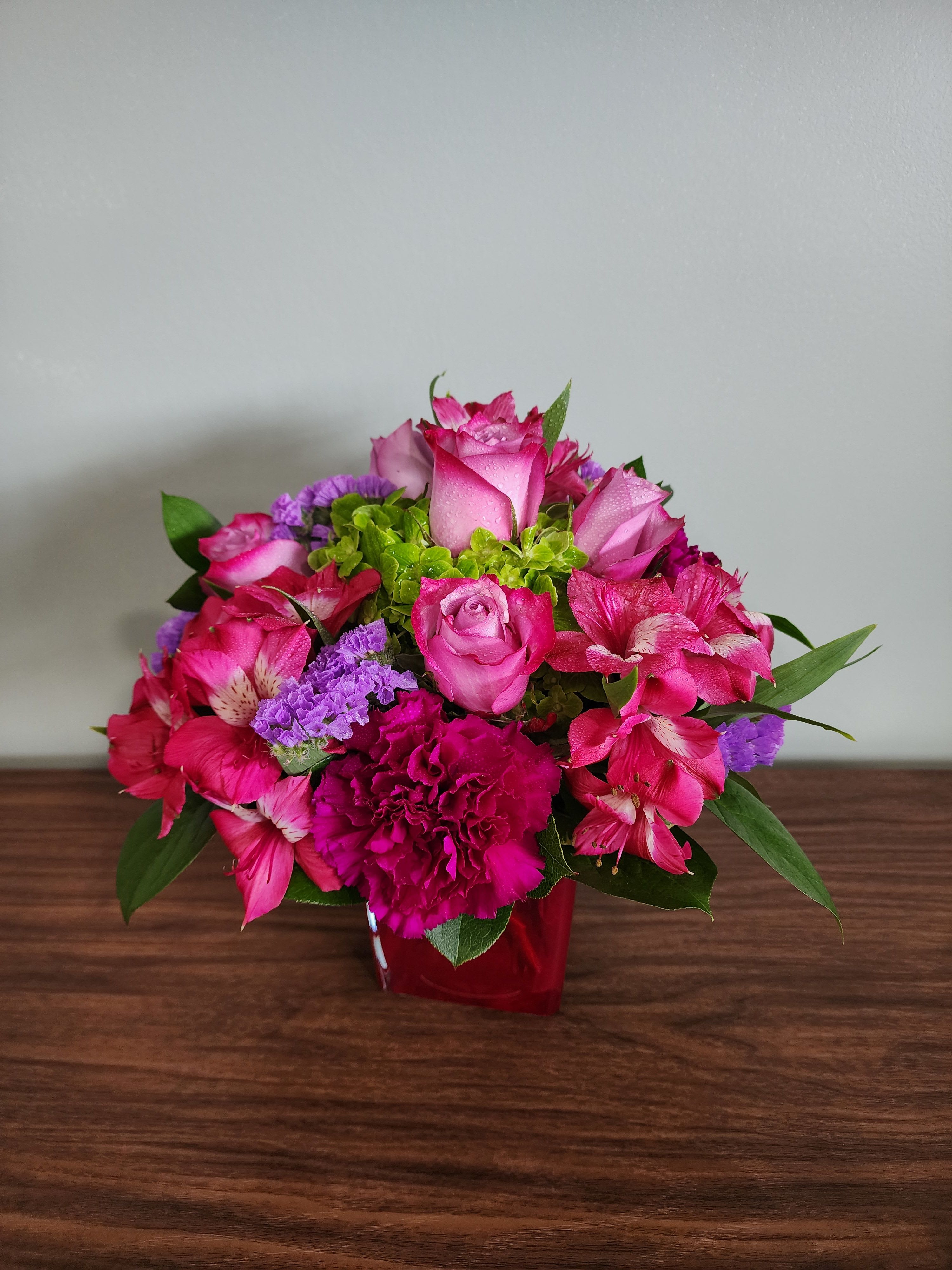 Pink roses and alstroemeria in a red vase