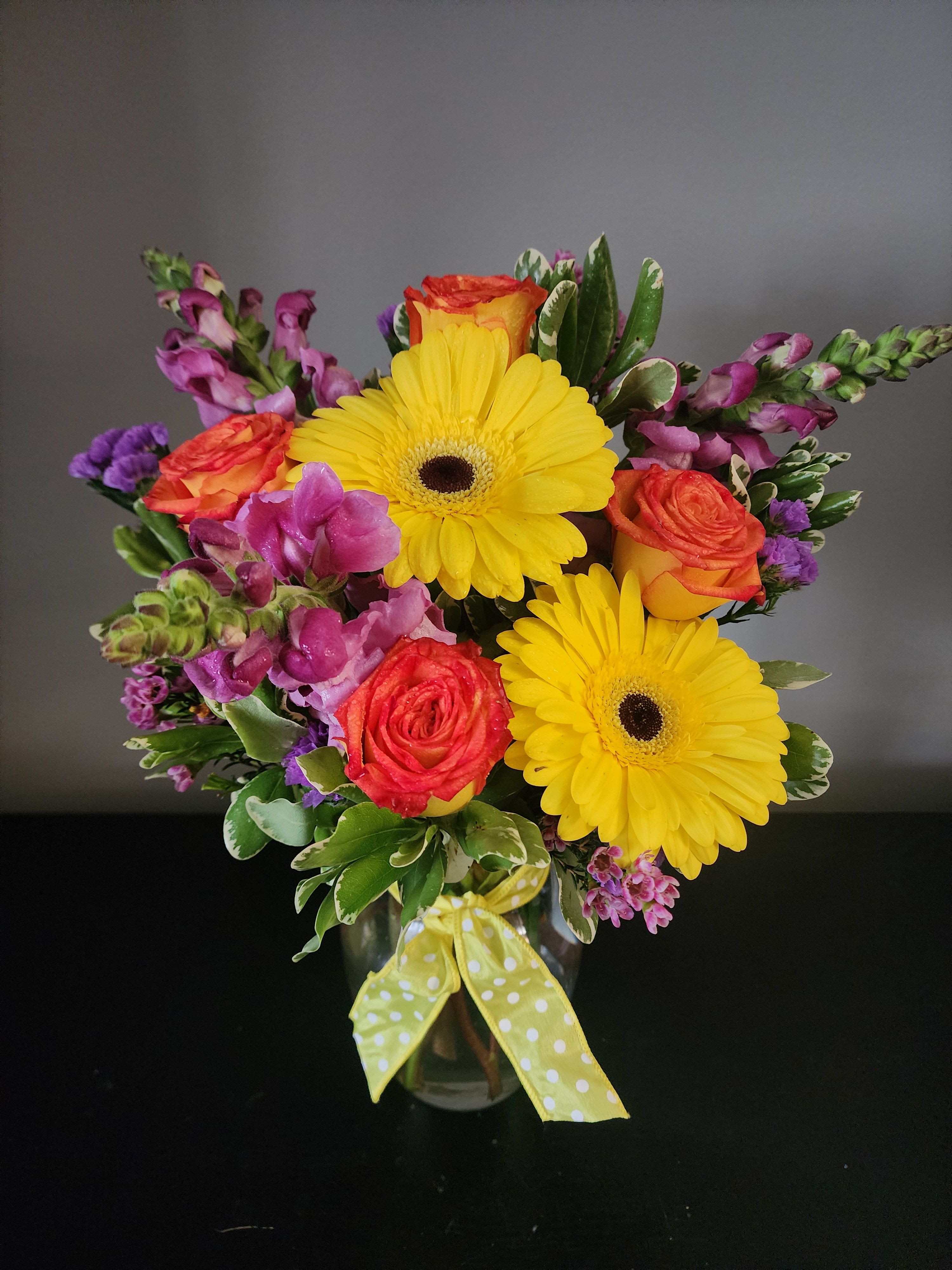 Bouquet of yellow gerbera daisies and orange roses in a glass vase