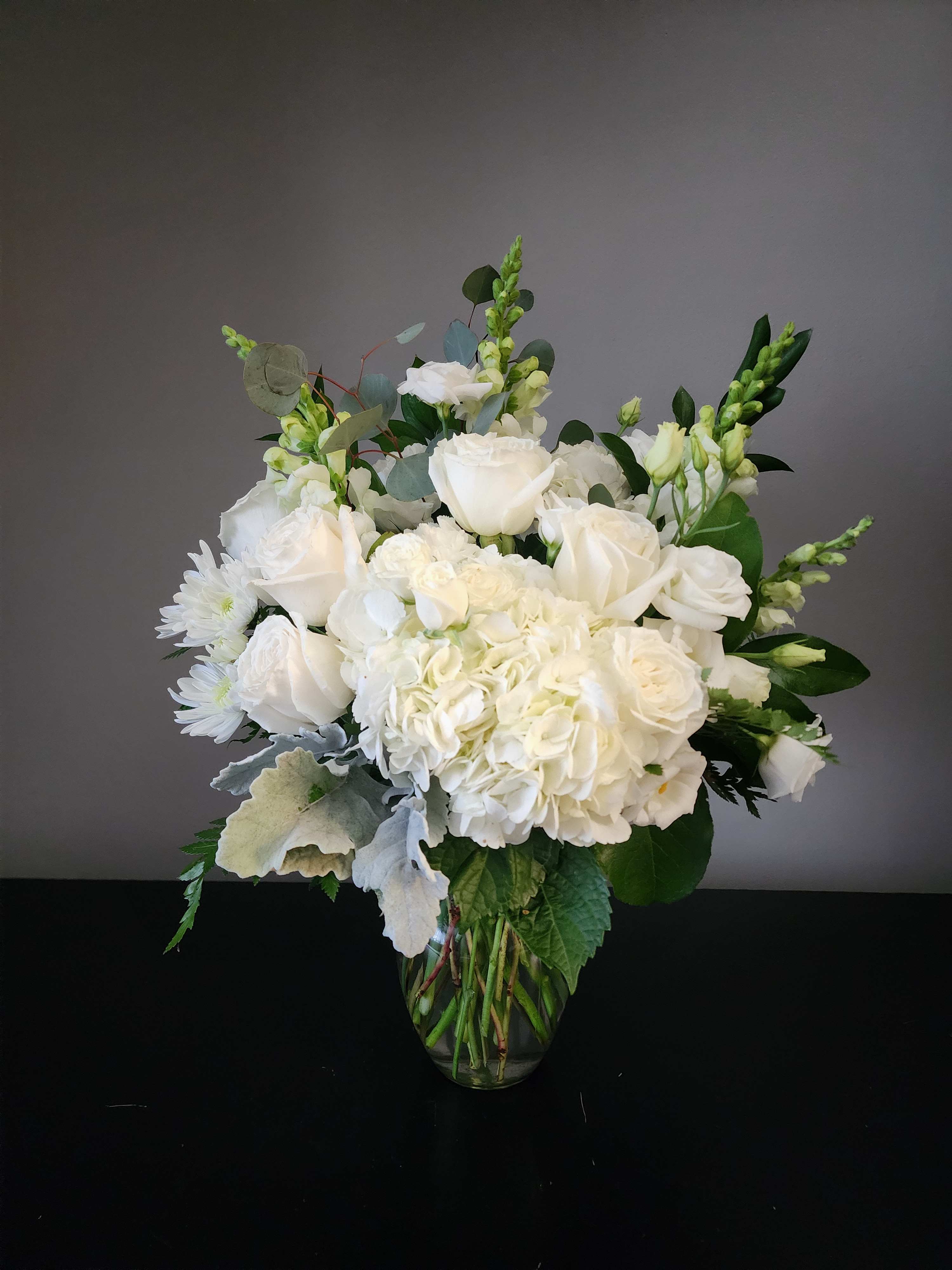 White roses and hydrangeas in a clear glass vase