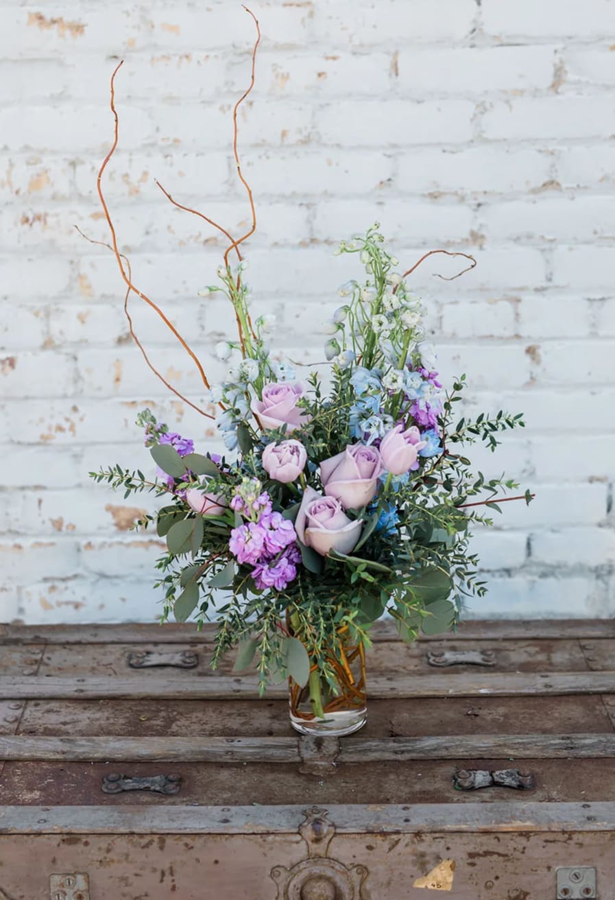 Lavender roses and purple flowers in a clear glass vase