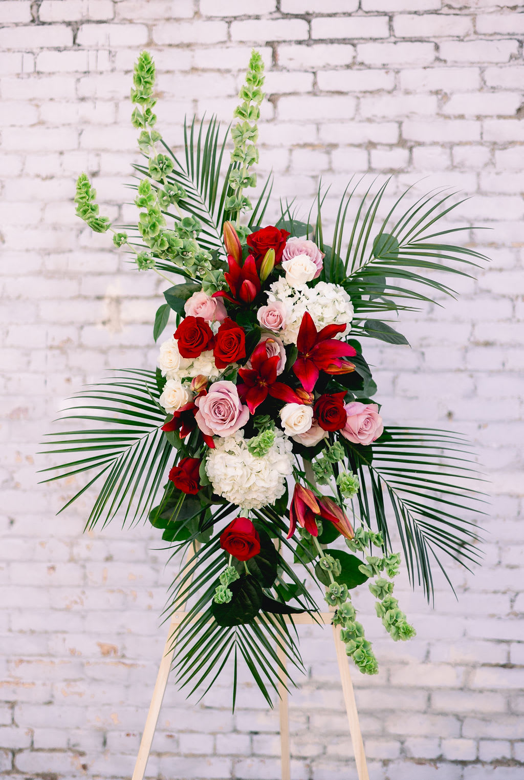 Standing floral spray with red and pink roses and lilies on an easel