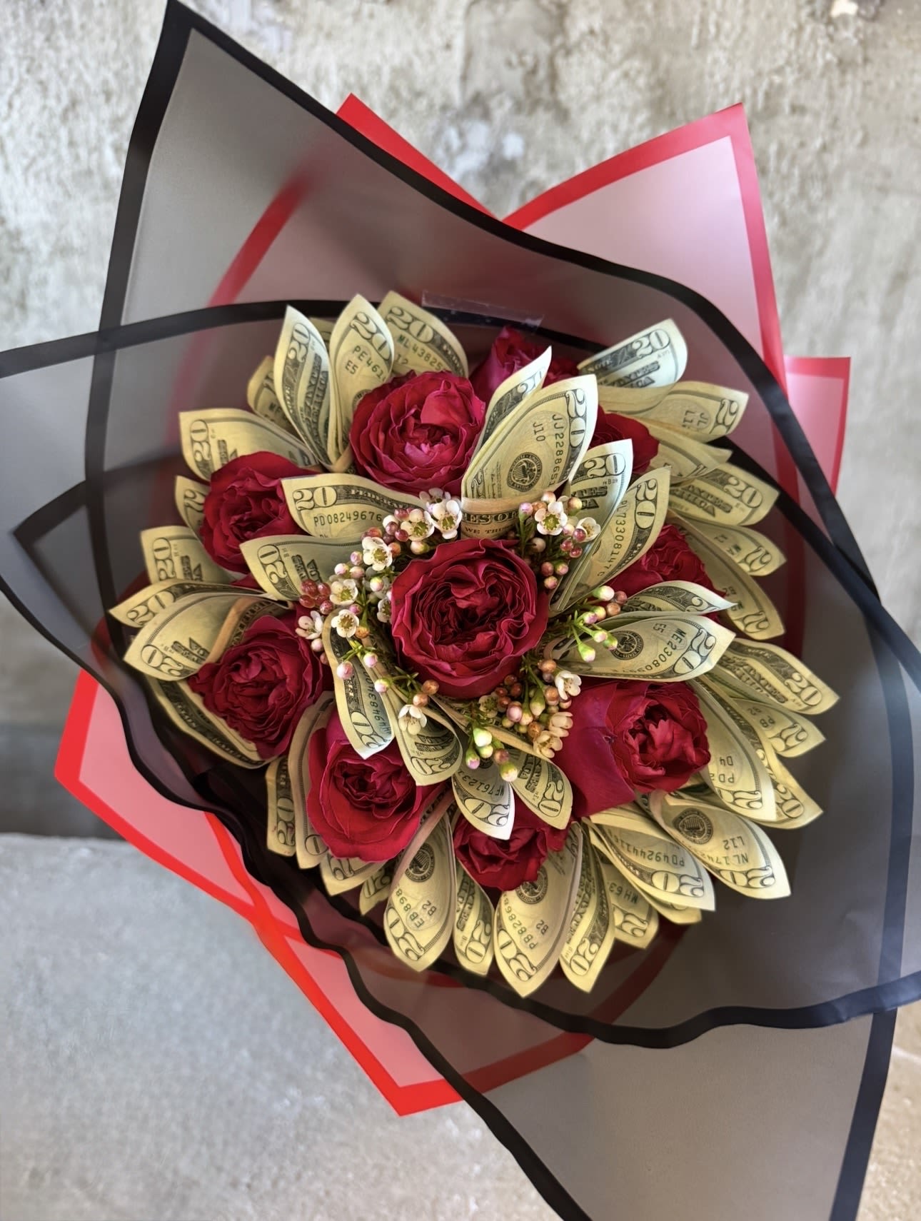 Bouquet of red roses wrapped with folded dollar bills and black-red paper