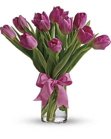 Bouquet of purple tulips tied with a pink ribbon in a clear glass vase