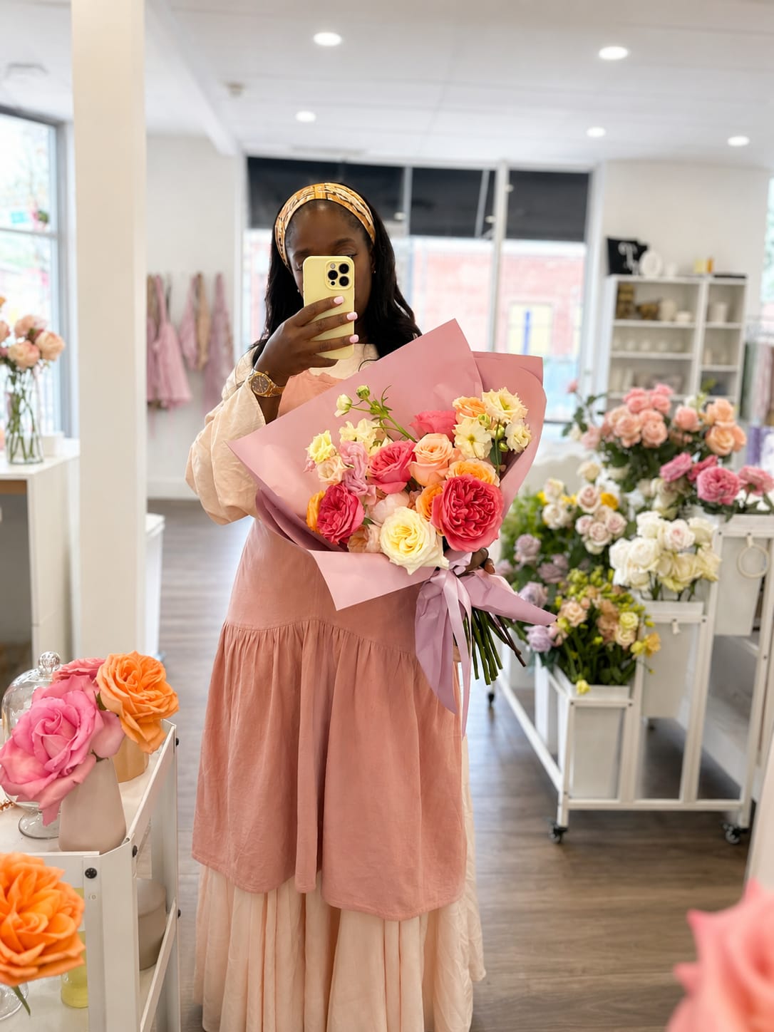Woman holding a pink-wrapped bouquet of multicolored roses