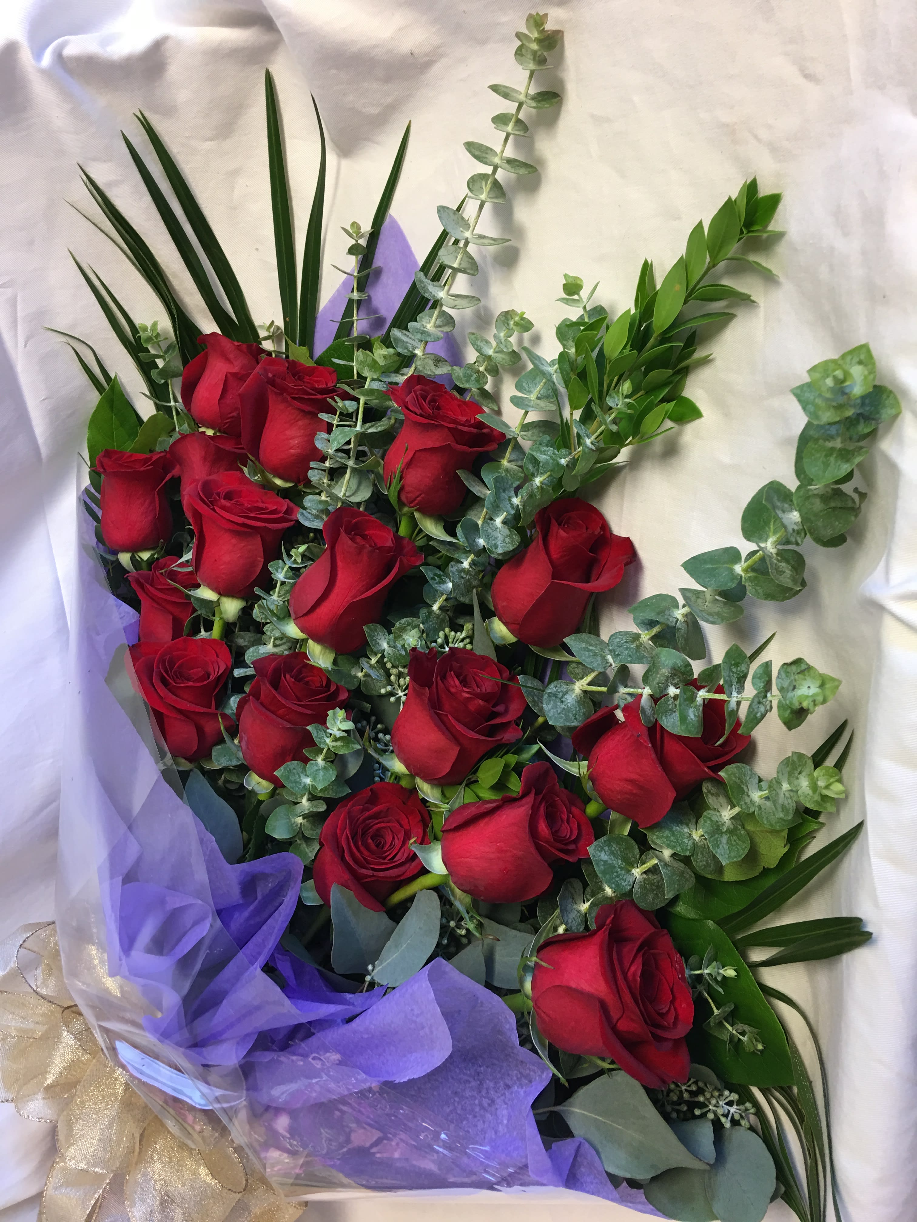 Bouquet of red roses with eucalyptus and purple wrapping