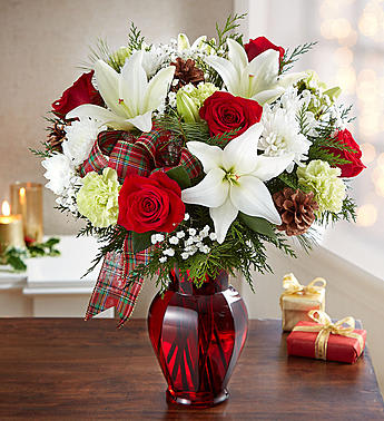 Red roses and white lilies in a red glass vase with plaid ribbon