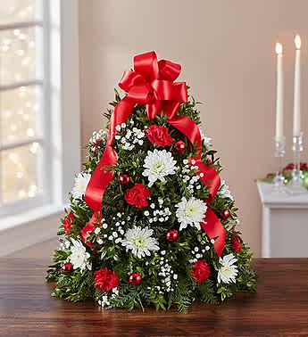 Christmas tree-shaped floral arrangement with red ribbon and white flowers
