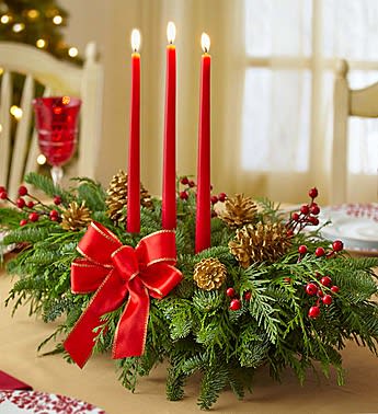 Holiday centerpiece with red candles, pinecones, and a red bow