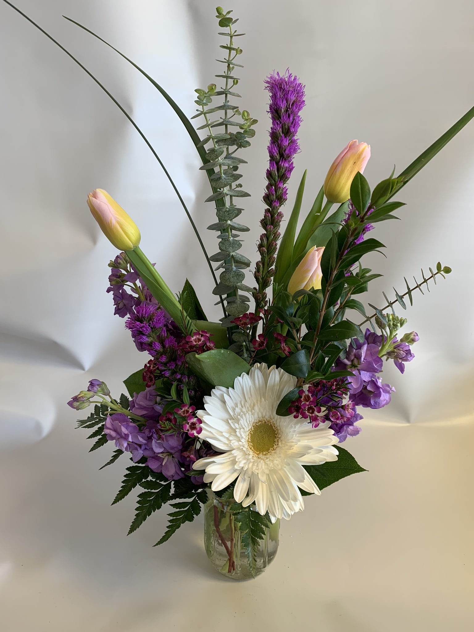 Mixed bouquet with white daisy and pink tulips in a glass vase