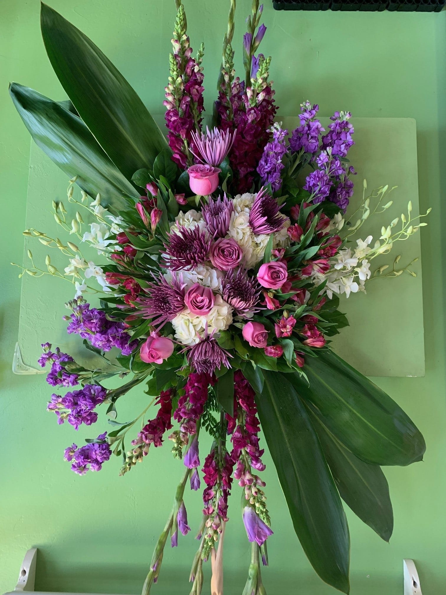 Large pink and purple floral arrangement with broad green leaves
