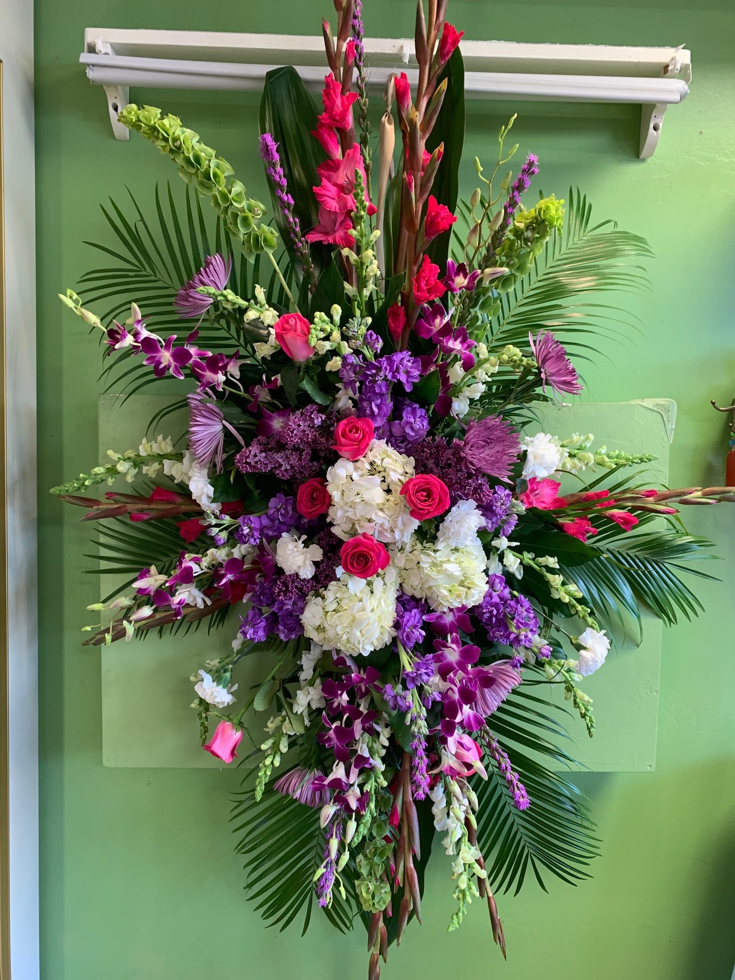Tall floral spray with pink, purple, and white flowers on palm fronds