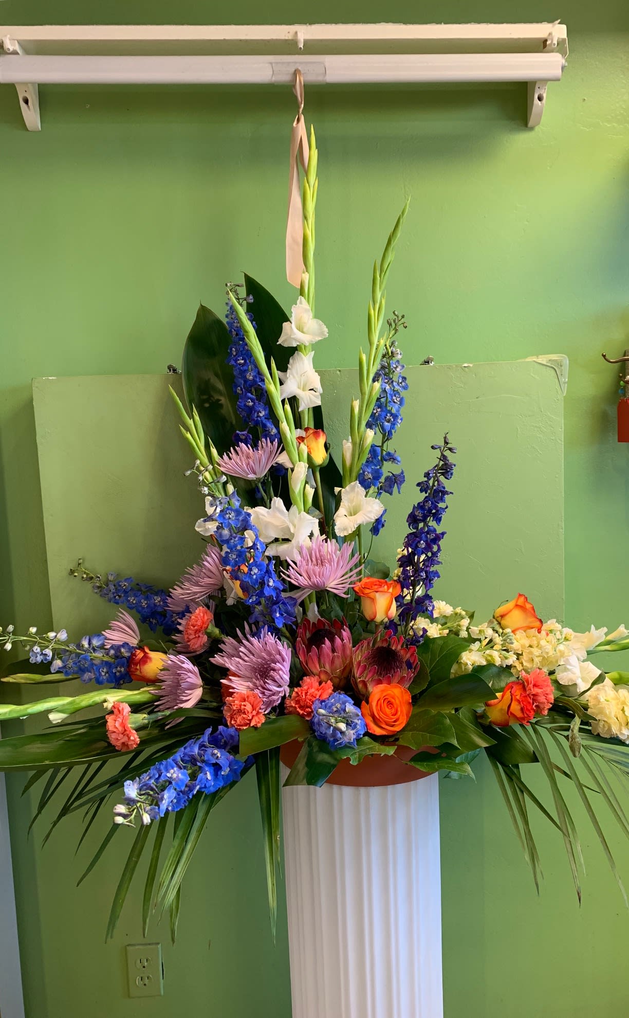 Tall mixed floral arrangement with blue, white, pink, and orange blooms
