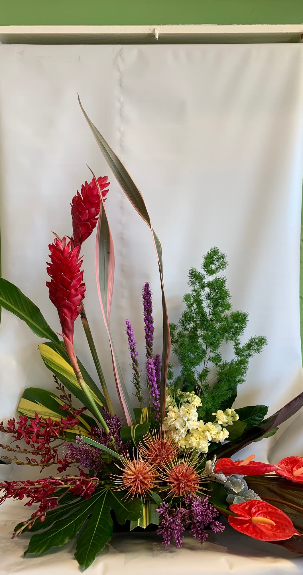 Tropical floral arrangement with red ginger, purple blooms, and red anthuriums