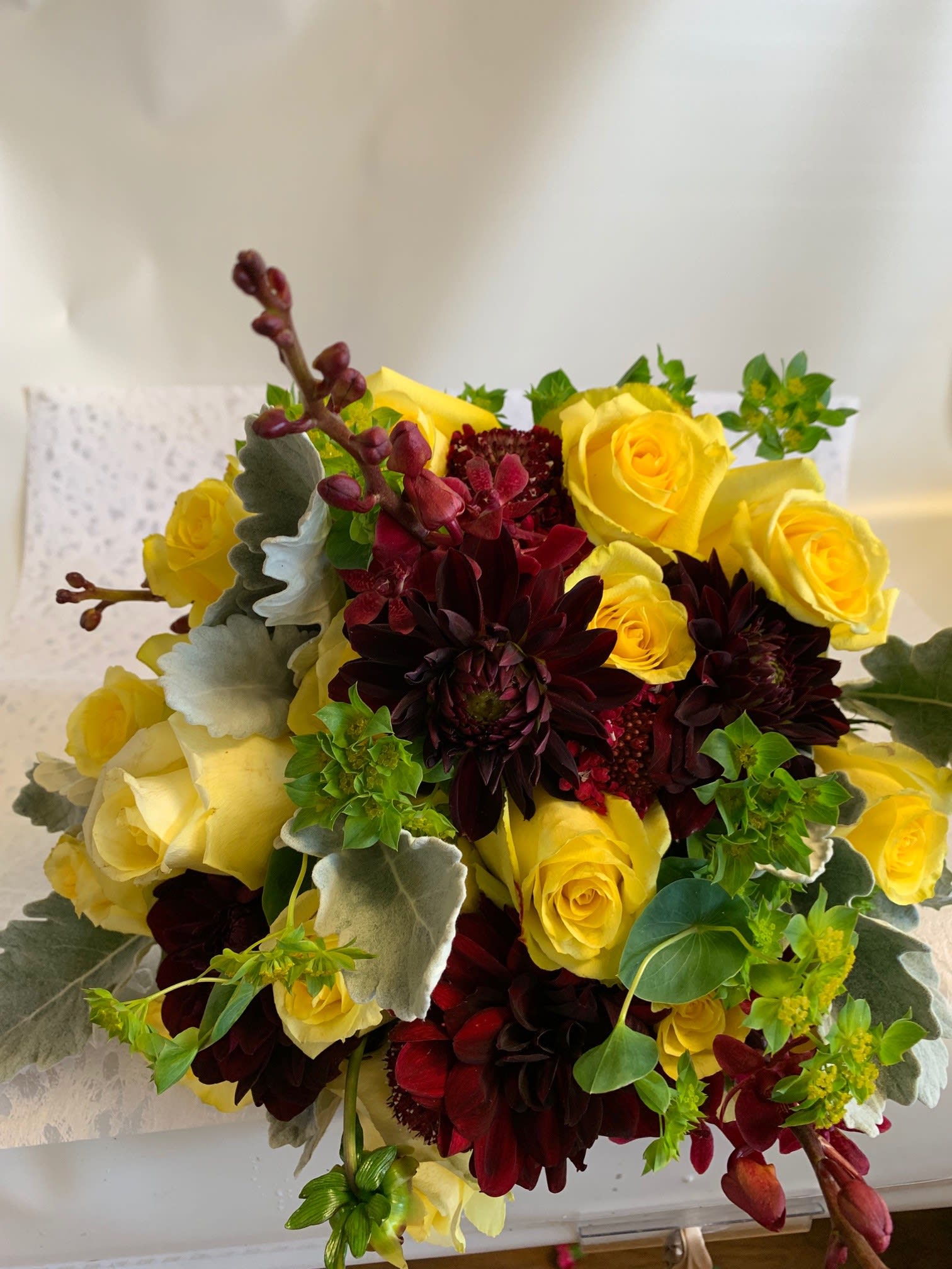 Bouquet of yellow roses and dark burgundy dahlias with silvery foliage