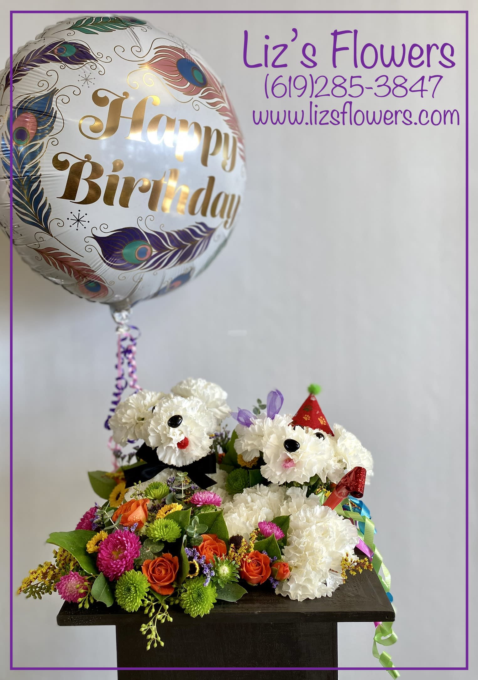 Birthday balloon above a flower arrangement with two white dog faces
