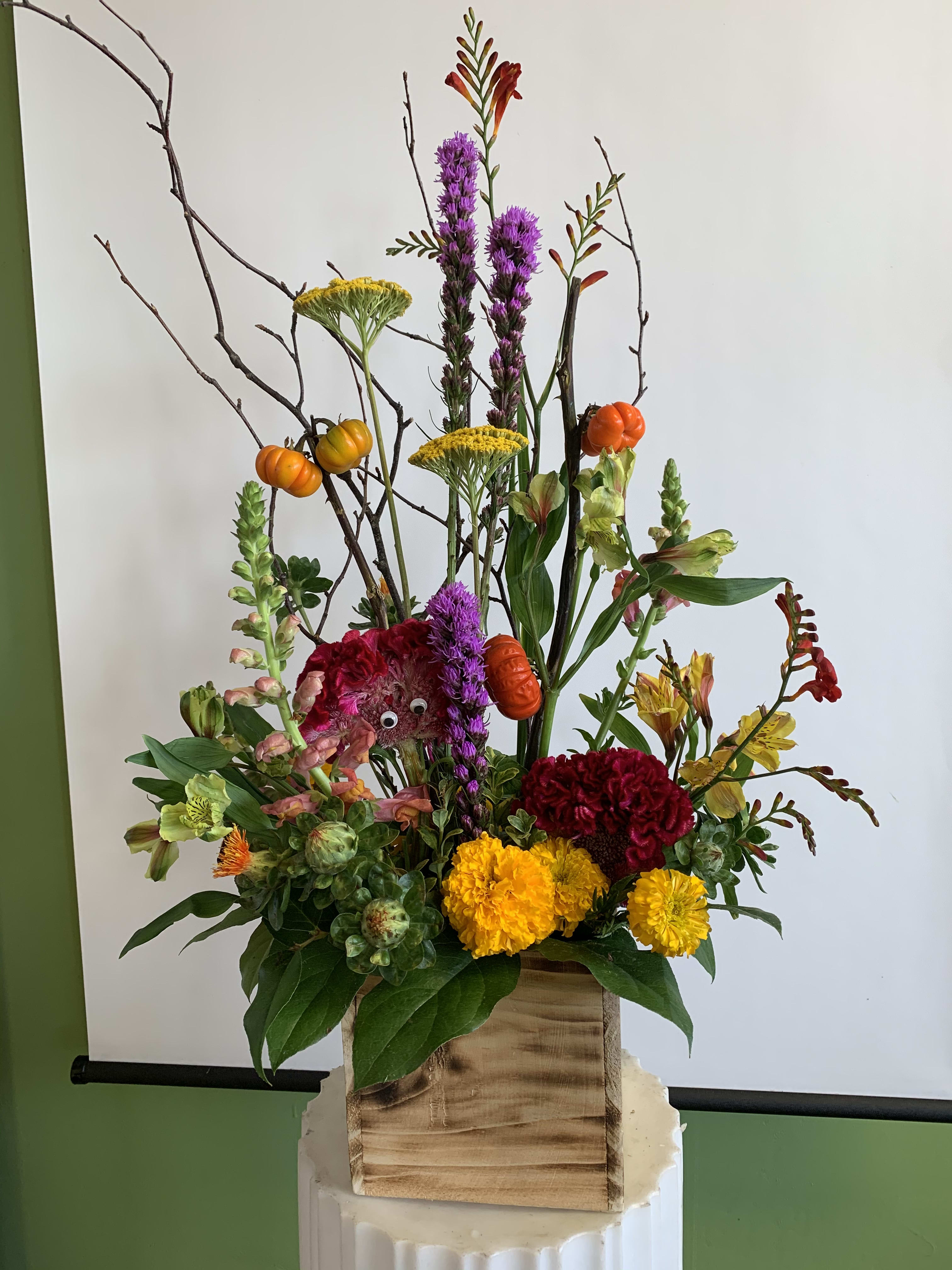 Tall mixed floral arrangement in a wooden box with orange accents