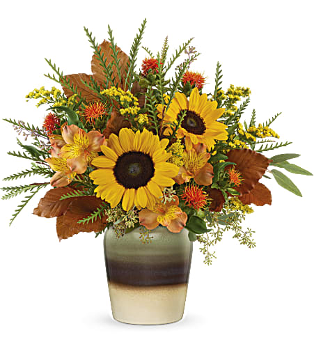 Teleflora's Thankfully Yours Bouquet - Full of fall cheer, this radiant autumnal sunflower arrangement arrives in a stunning stoneware vase with reactive glaze and distressed details, making it a favorite year-round accent piece or kitchen crock! 
