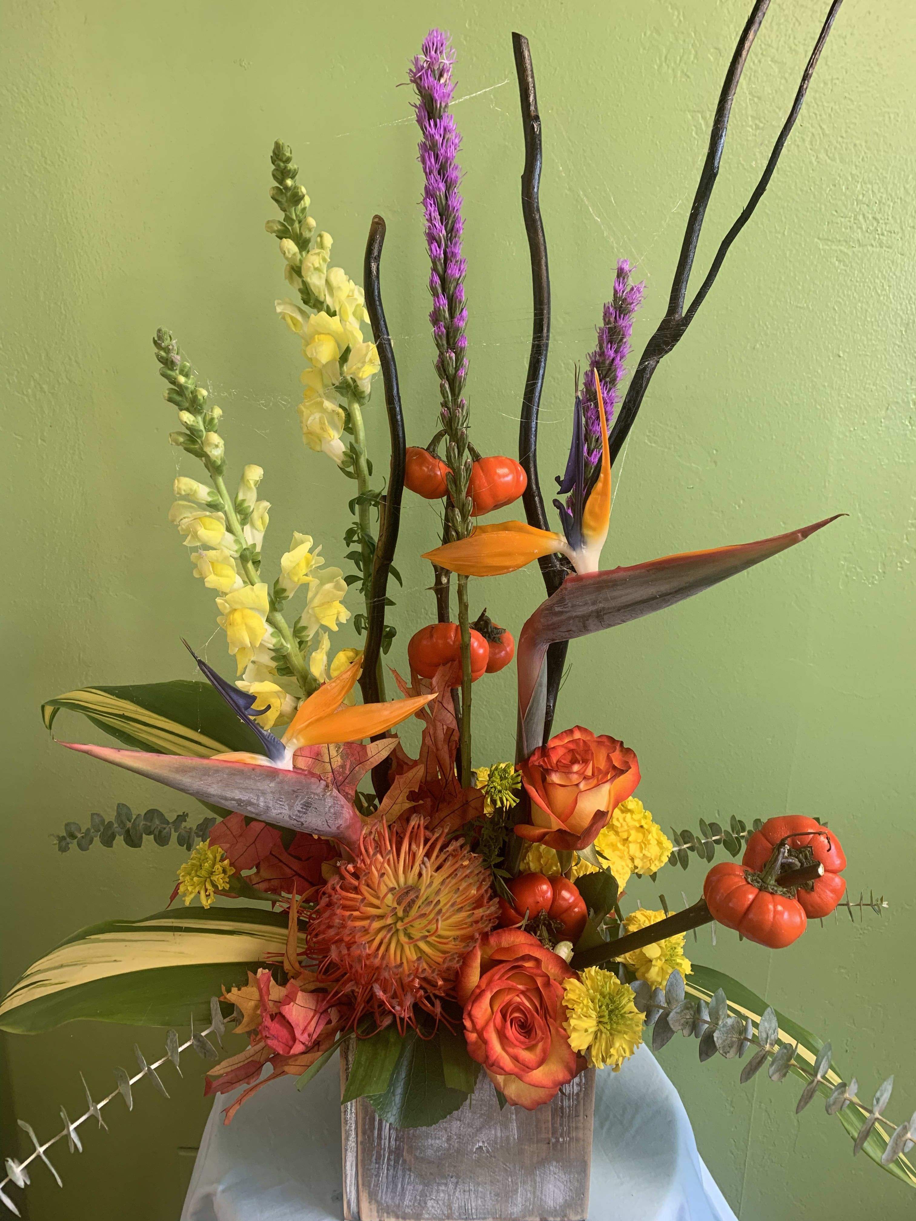 Tropical floral arrangement with orange roses and bird-of-paradise blooms