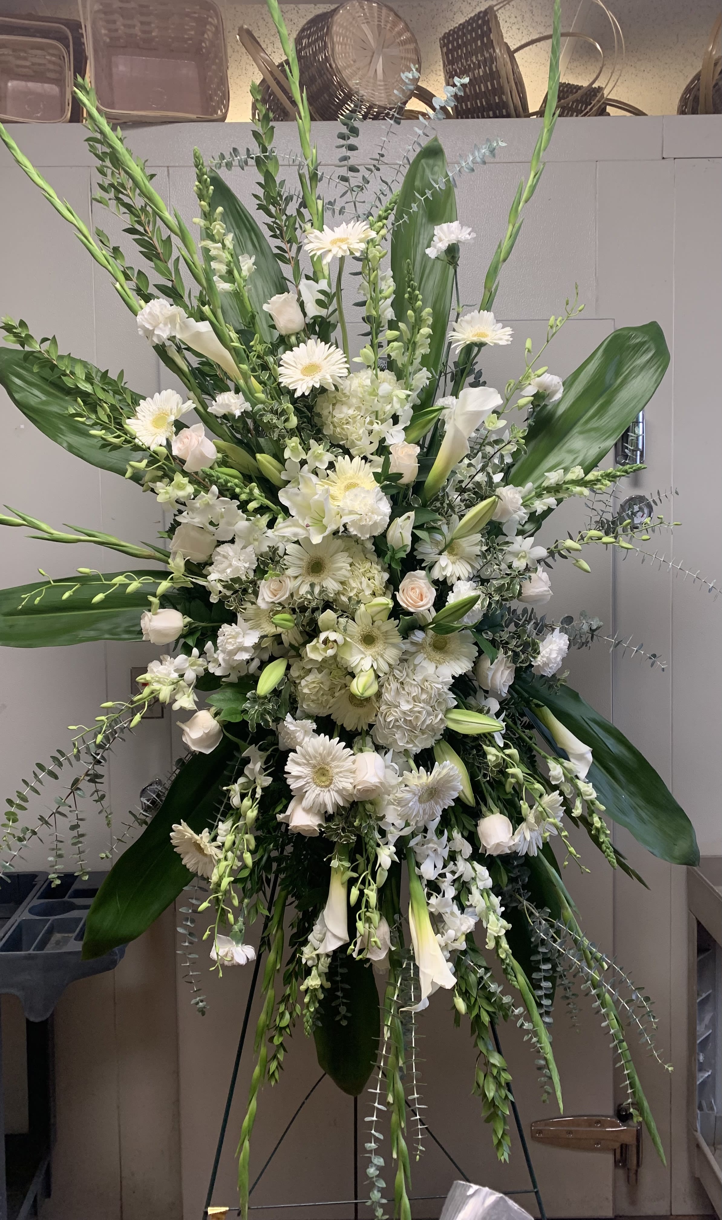 Large white floral standing spray with lilies, roses, and daisies