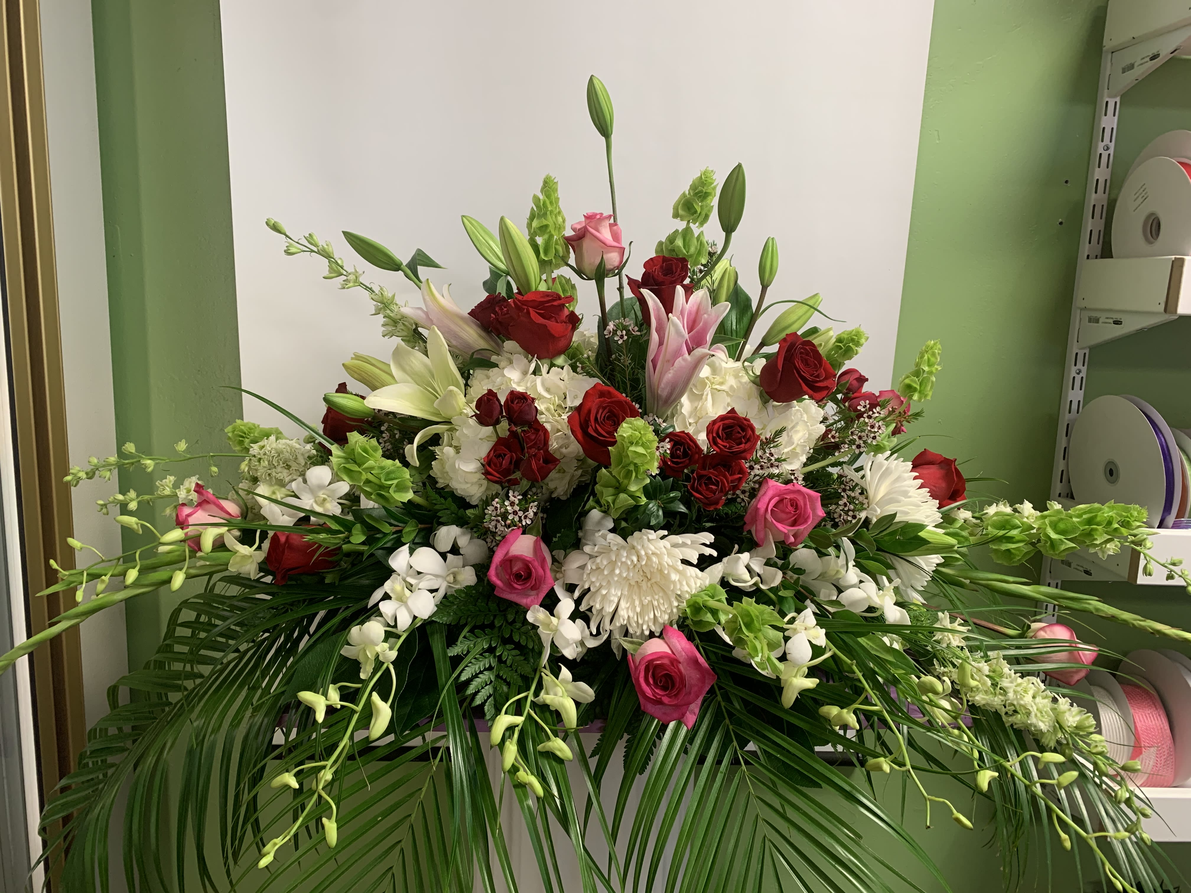 Large floral arrangement with red, pink, and white blooms in a low container