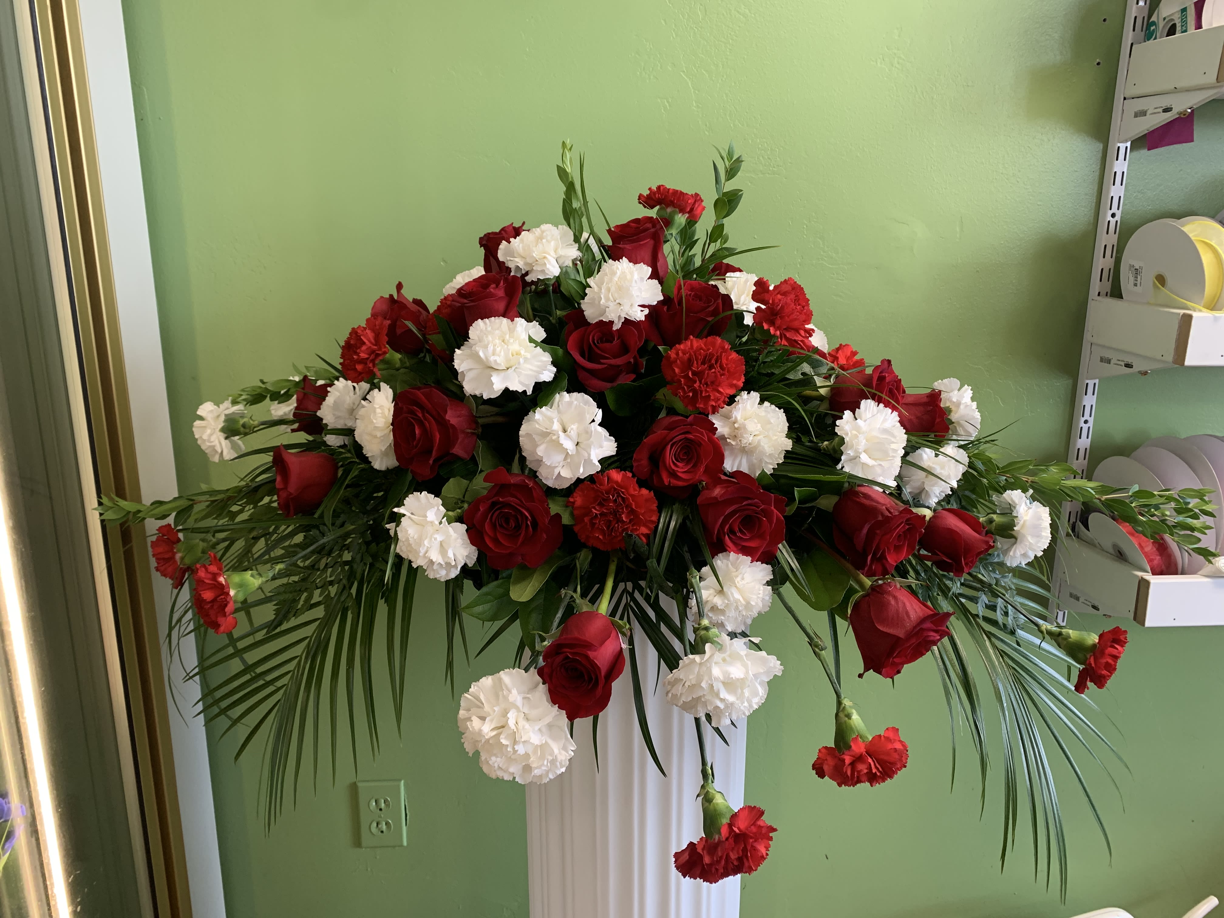 Red roses and white carnations in a tall pedestal arrangement