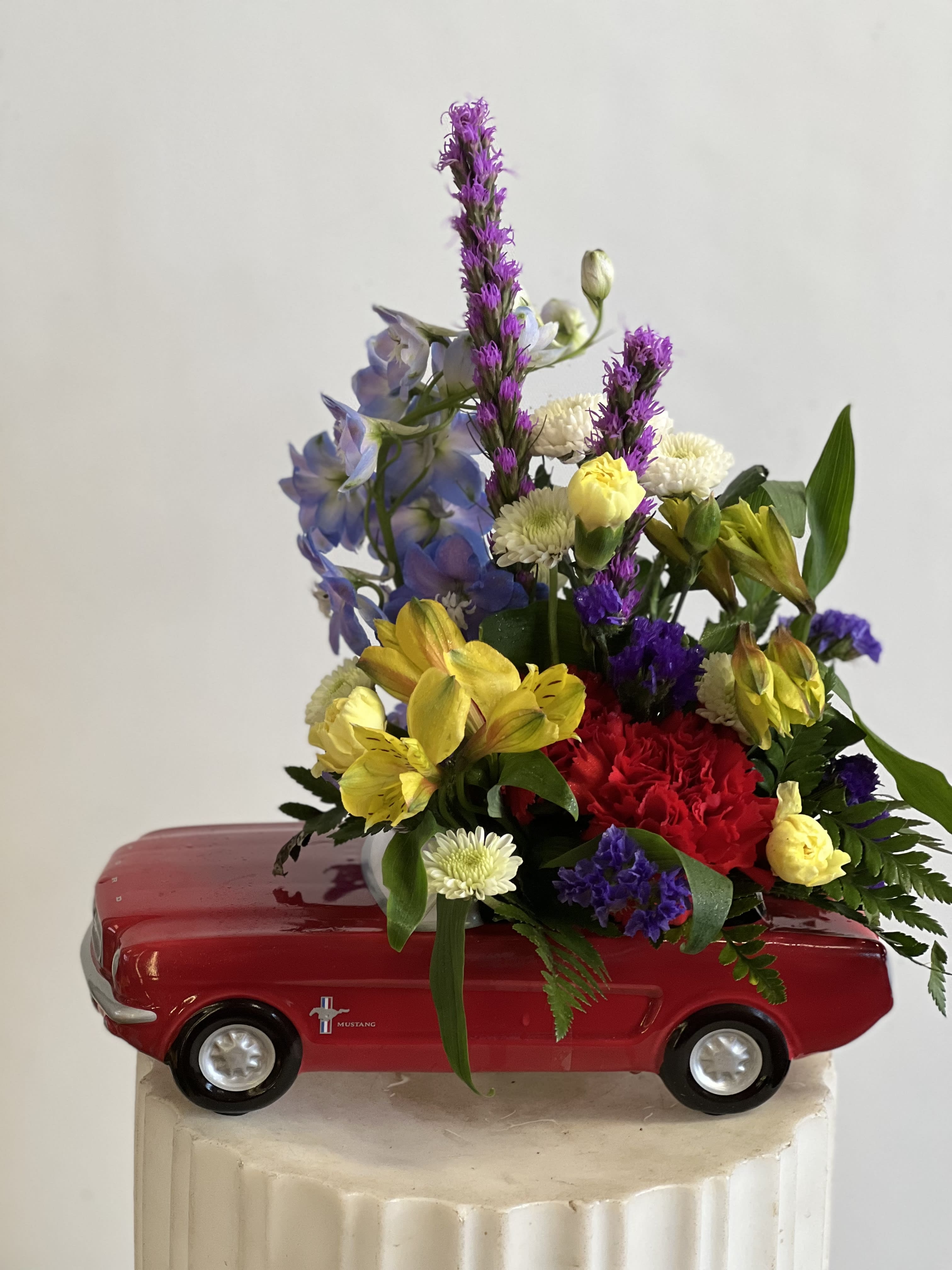 Mixed flower arrangement in a red toy car container