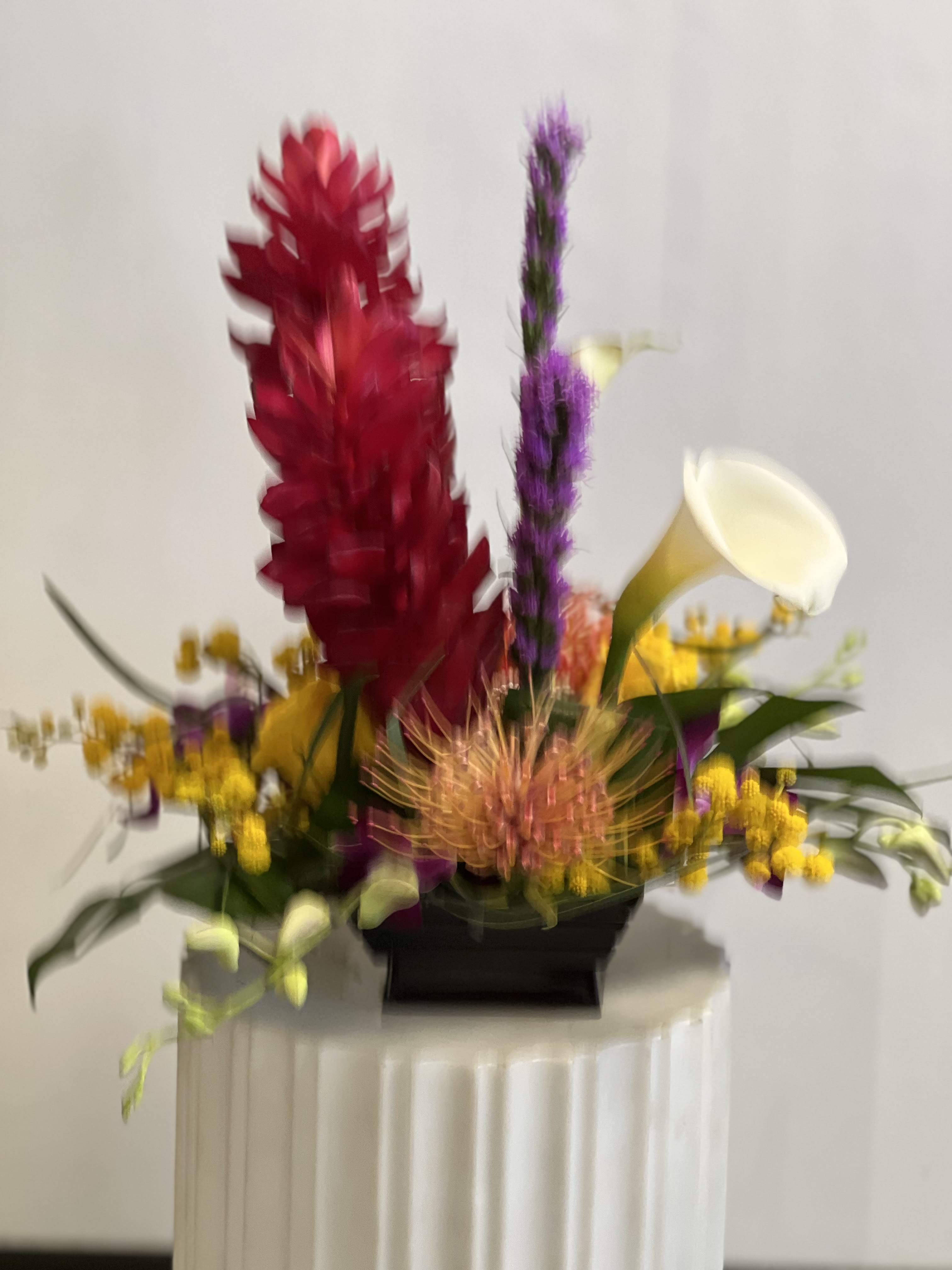 Colorful floral arrangement with red, purple, yellow, and white blooms in a black container
