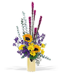Tall bouquet of sunflowers and purple flowers in a yellow vase