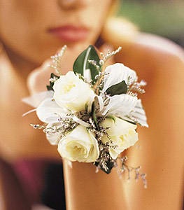 White floral wrist corsage with roses and ribbon on a person's wrist