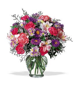 Mixed bouquet of pink, purple, and white flowers in a clear glass vase