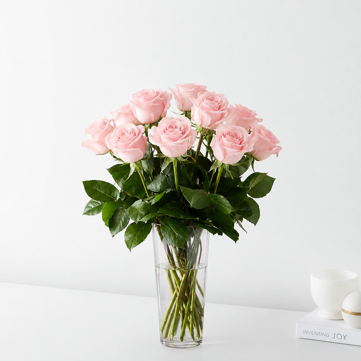 Dozen Light Pink Roses  - Soft, elegant, and timeless, this bouquet of premium light pink roses is beautifully arranged in a clear glass vase with lush greenery. A graceful expression of admiration, gratitude, and affection, it's the perfect gift for birthdays, anniversaries, congratulations, or simply to brighten someone's day.