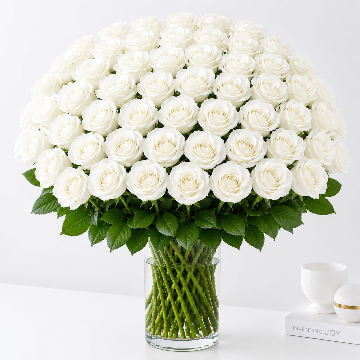 48 White Roses - Make an unforgettable statement with this breathtaking bouquet of 48 premium long-stem white roses. Expertly arranged in a clear glass vase with lush greenery, this timeless design is the perfect expression of love, romance, admiration, or celebration. Ideal for anniversaries, birthdays, Valentine's Day, or any occasion that deserves a grand gesture.