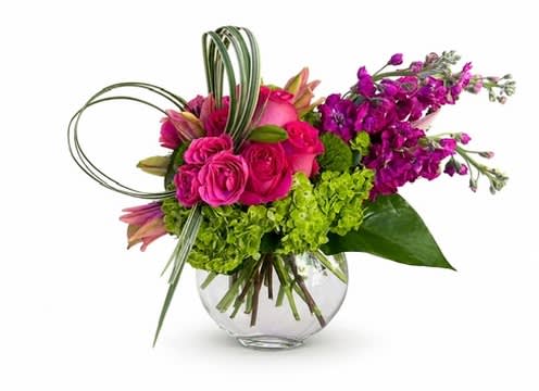 Pink roses and purple flowers in a clear glass vase