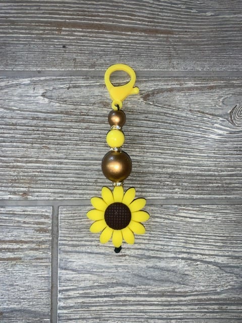Yellow sunflower bead charm on a gray wood surface