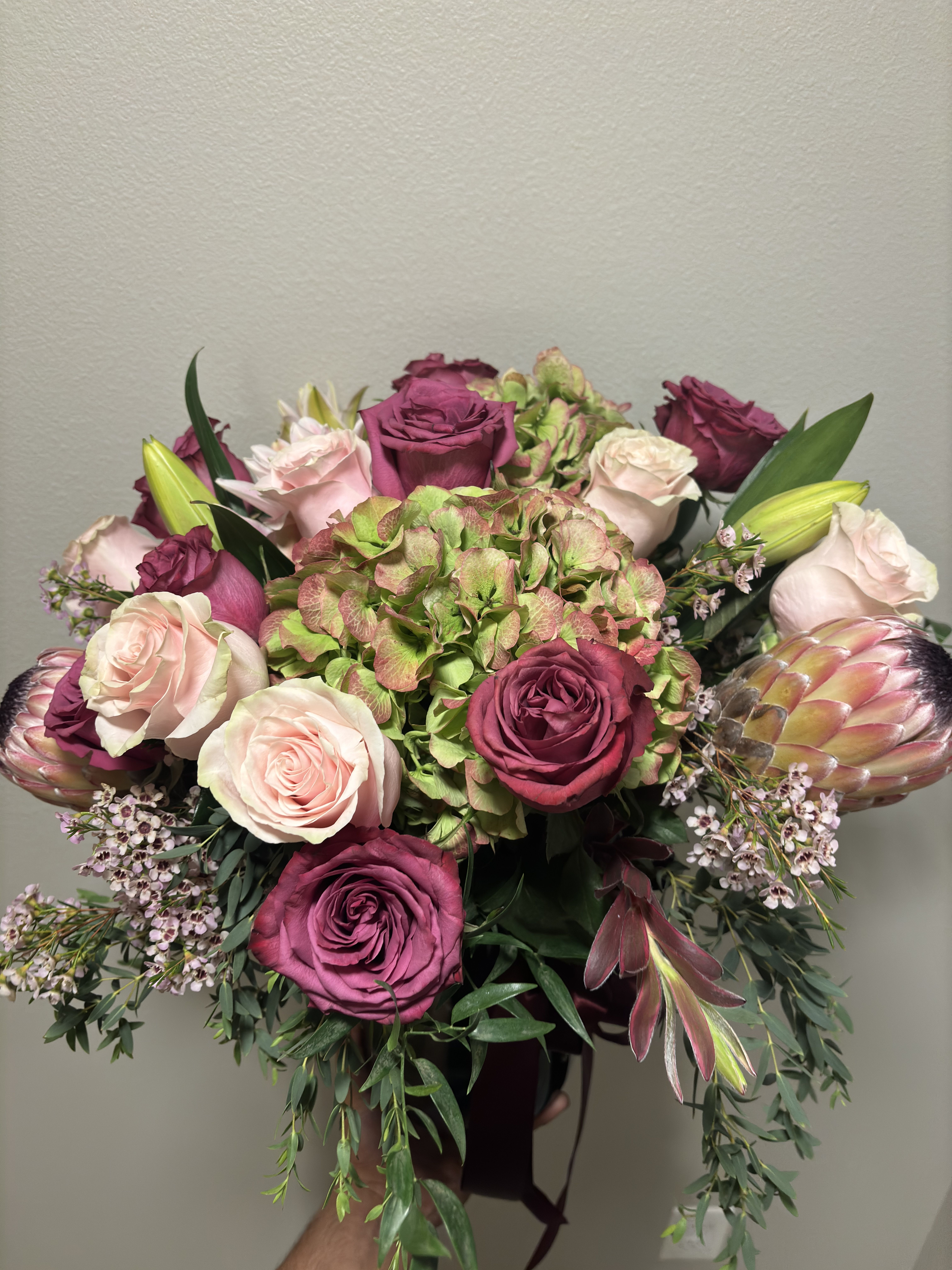 Bouquet of pink and magenta roses with hydrangea and protea