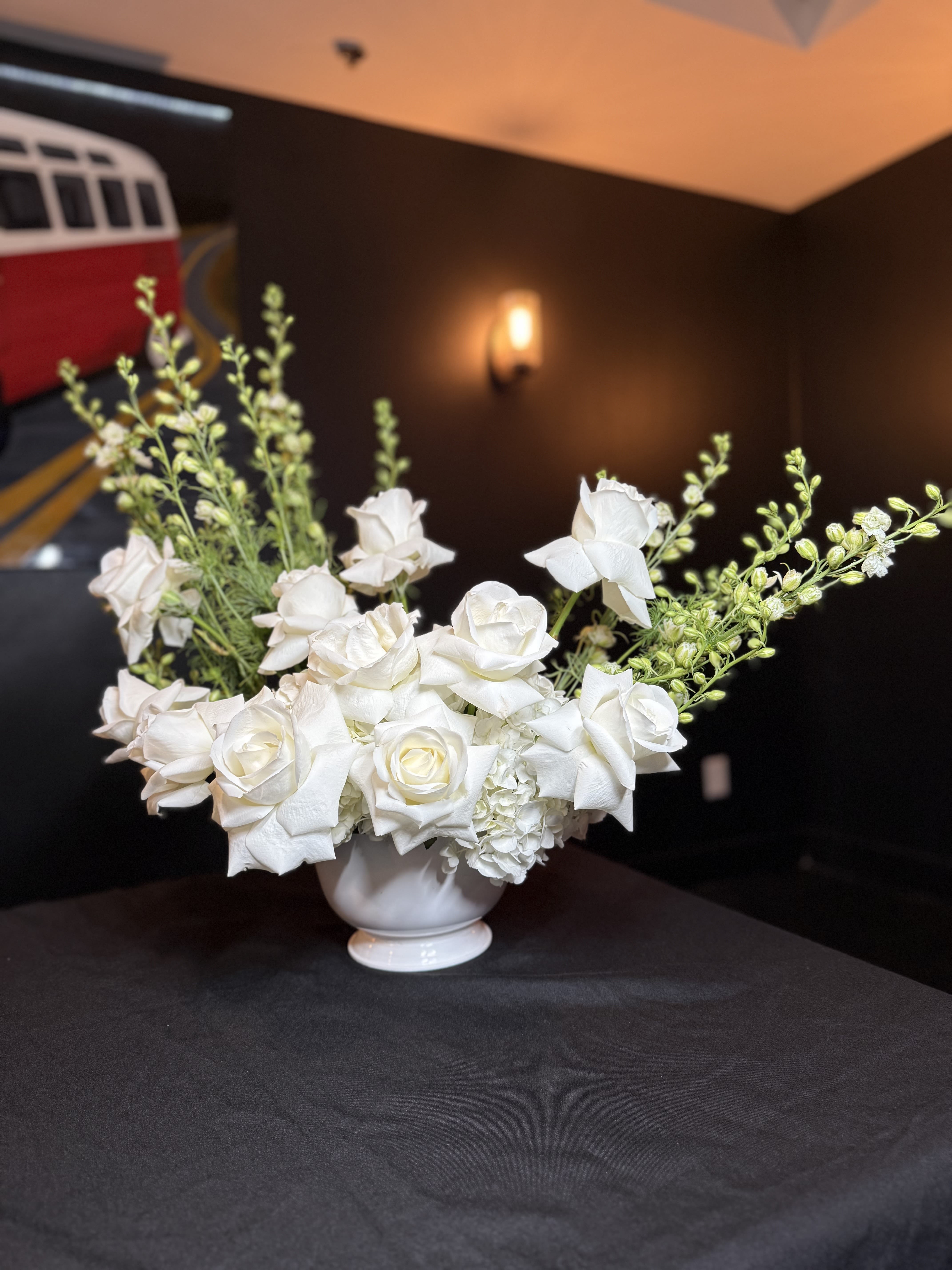White rose arrangement in a white pedestal vase
