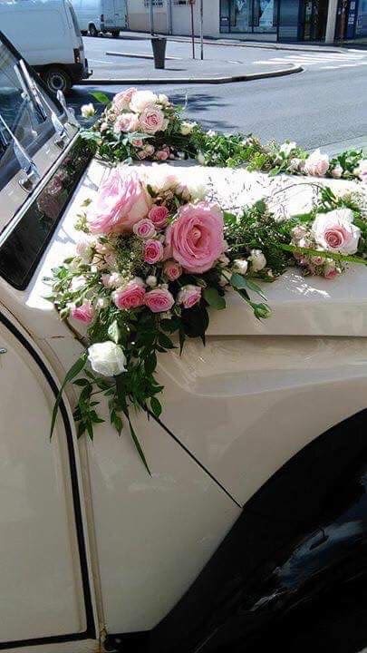 Pink and white floral arrangement draped over a car hood