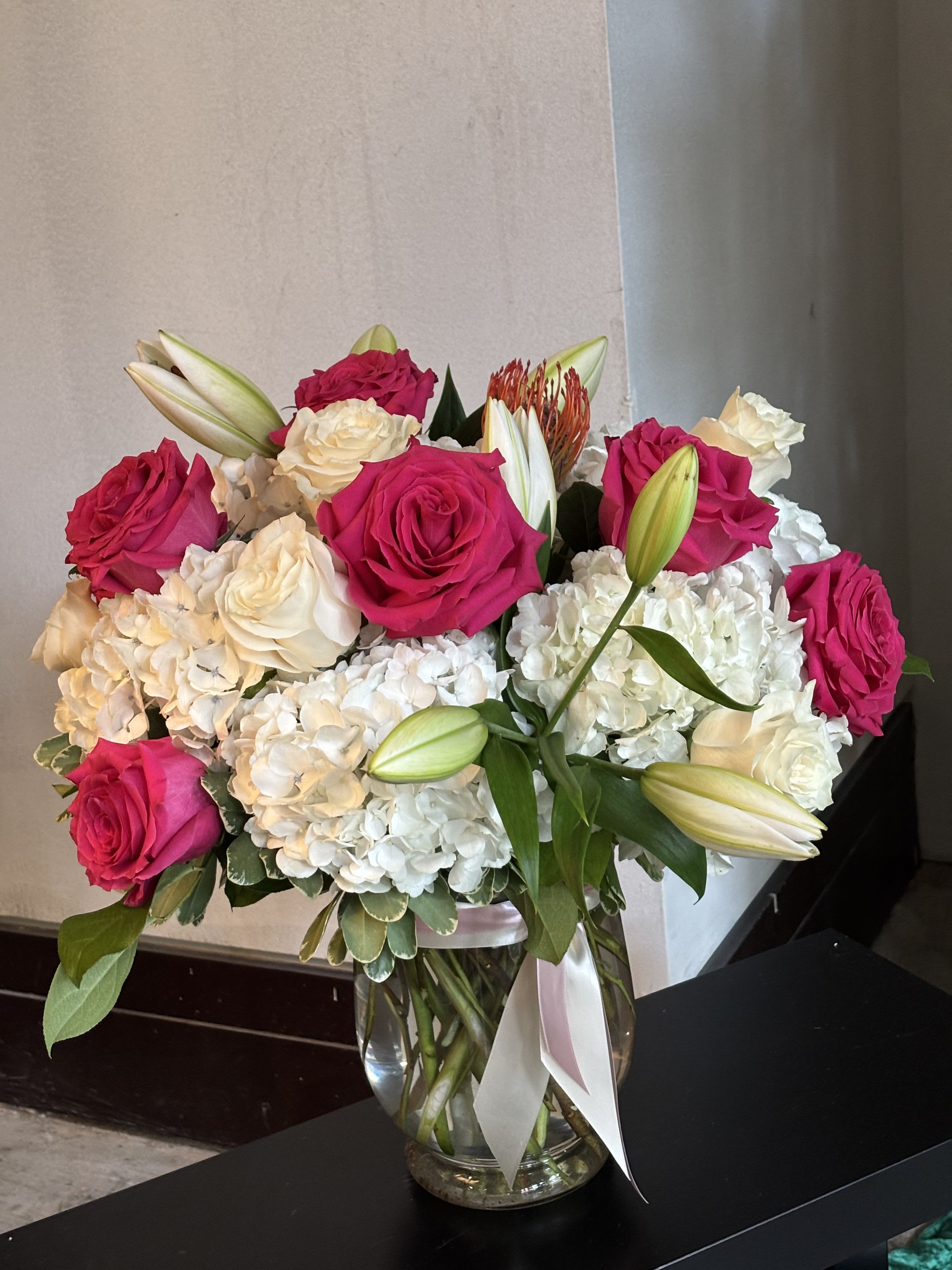 Pink and white roses with lilies and hydrangeas in a glass vase