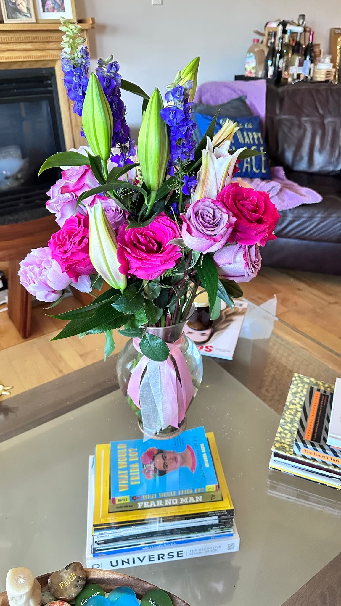 Bouquet of pink roses, purple lilies, and blue delphinium in a glass vase