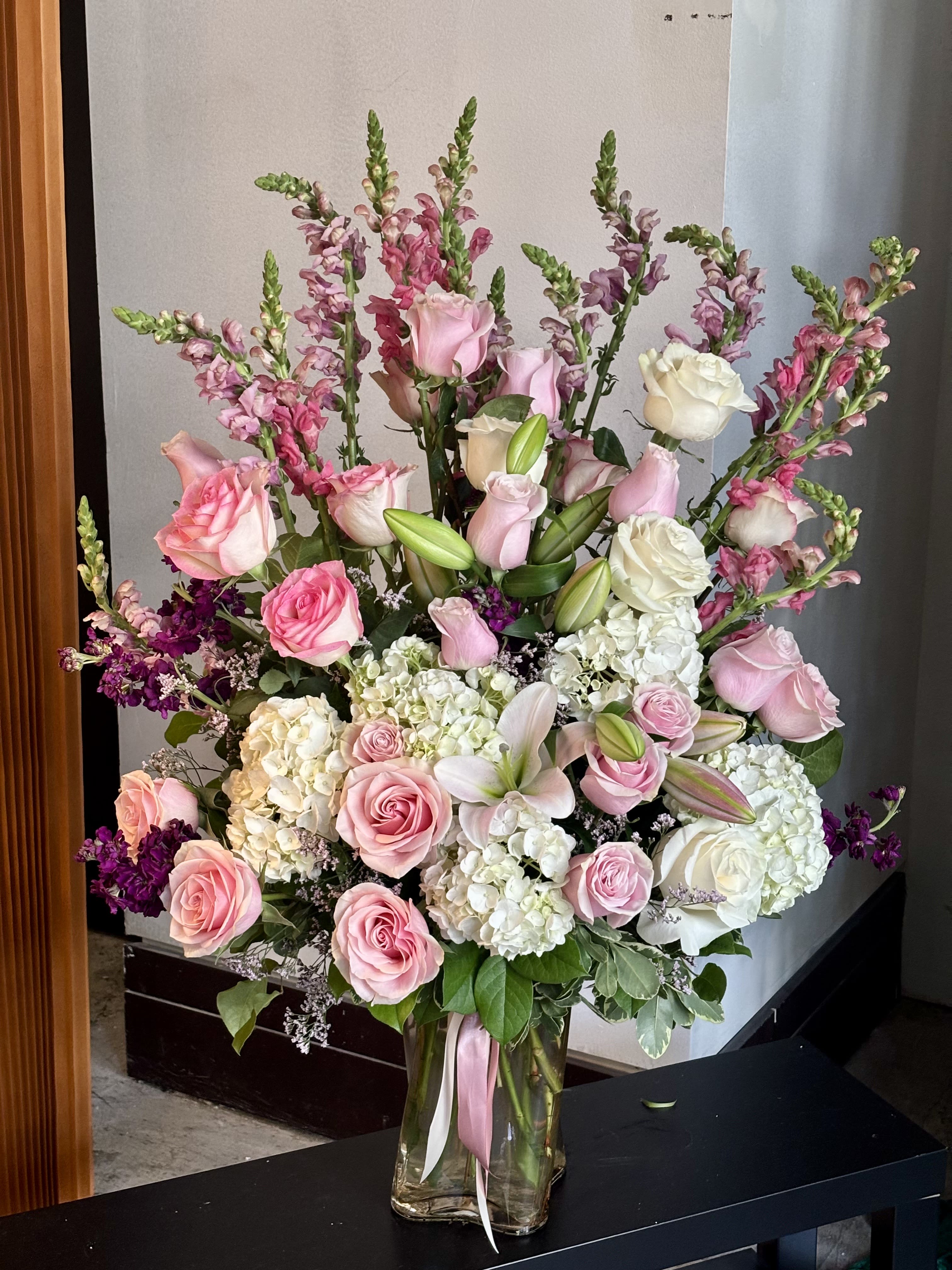 Large pink and white flower arrangement in a glass vase