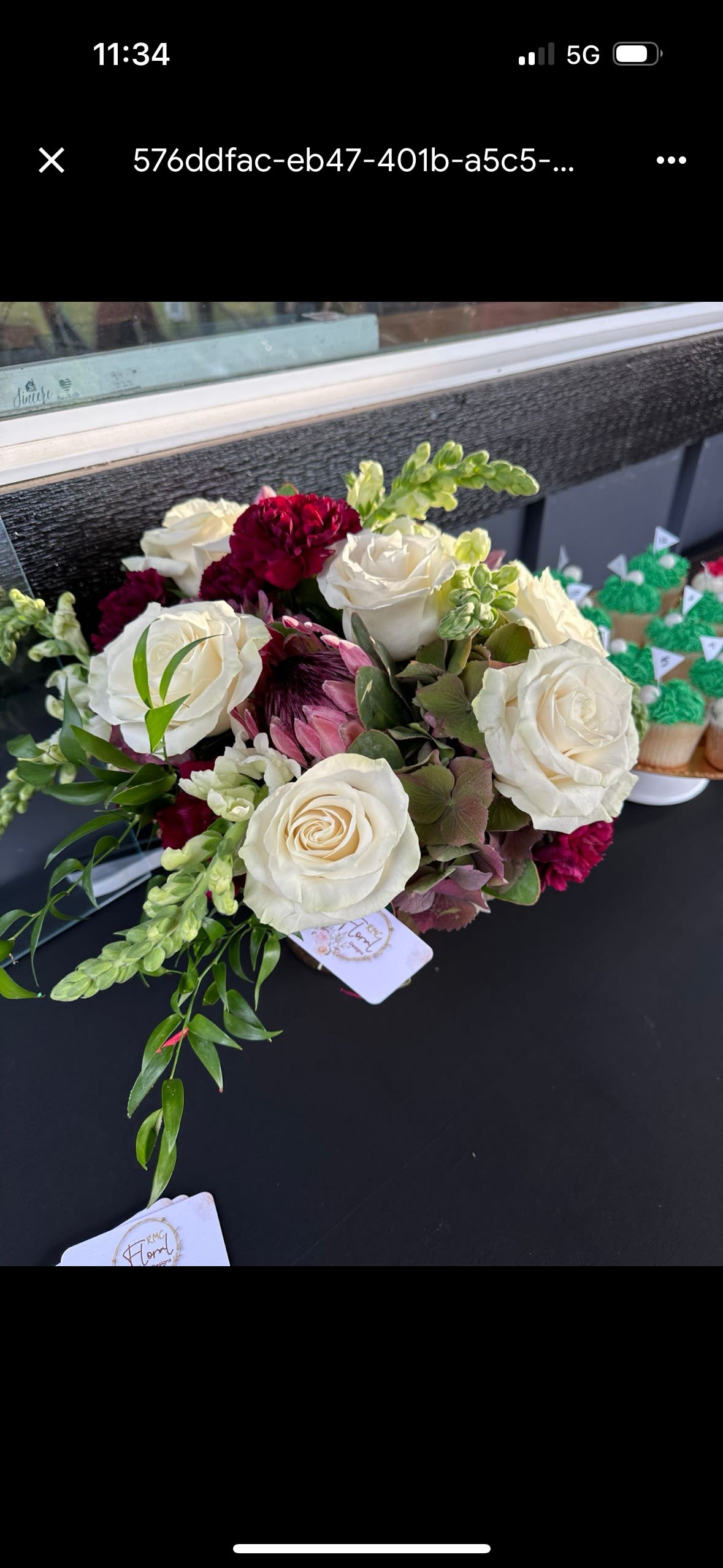 Bouquet of white roses with burgundy blooms and green accents