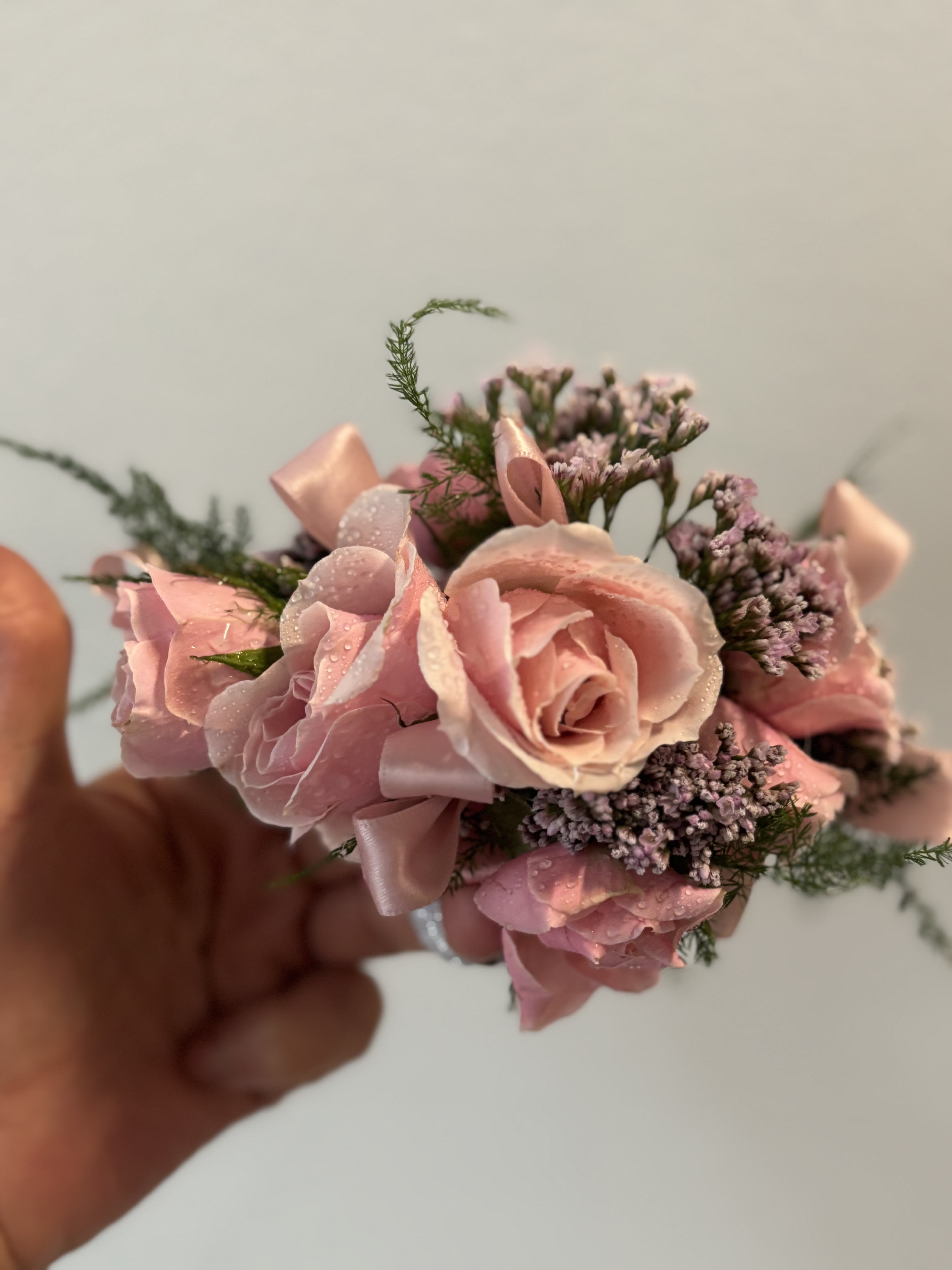 Small pink rose corsage with ribbon and tiny purple filler flowers