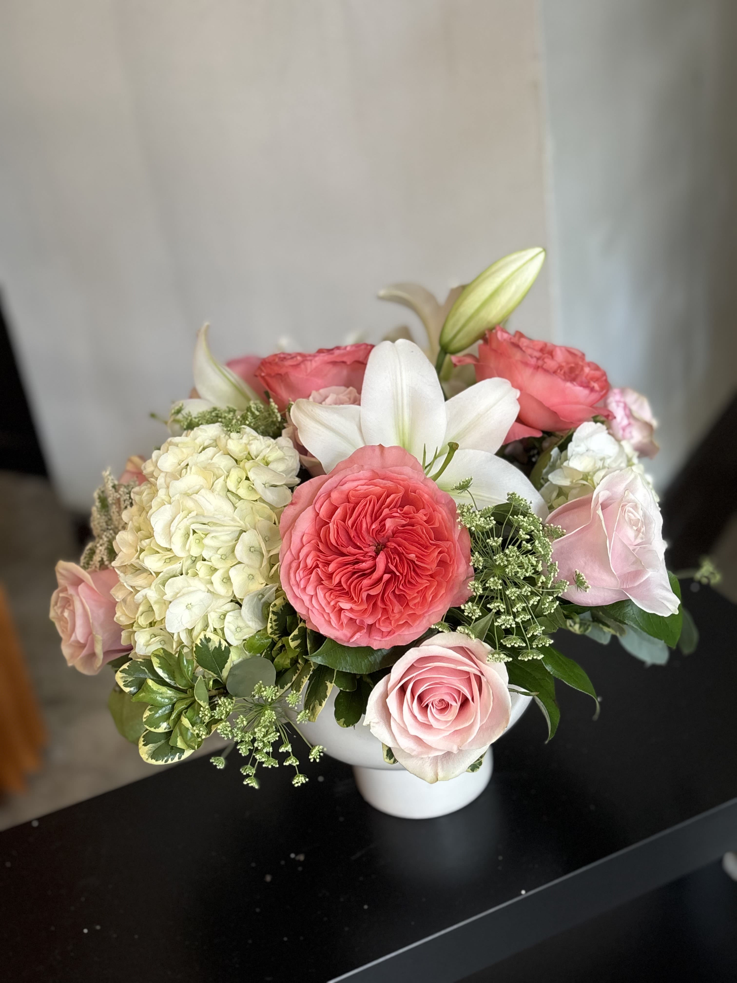Pink and white rose arrangement with a white lily in a vase