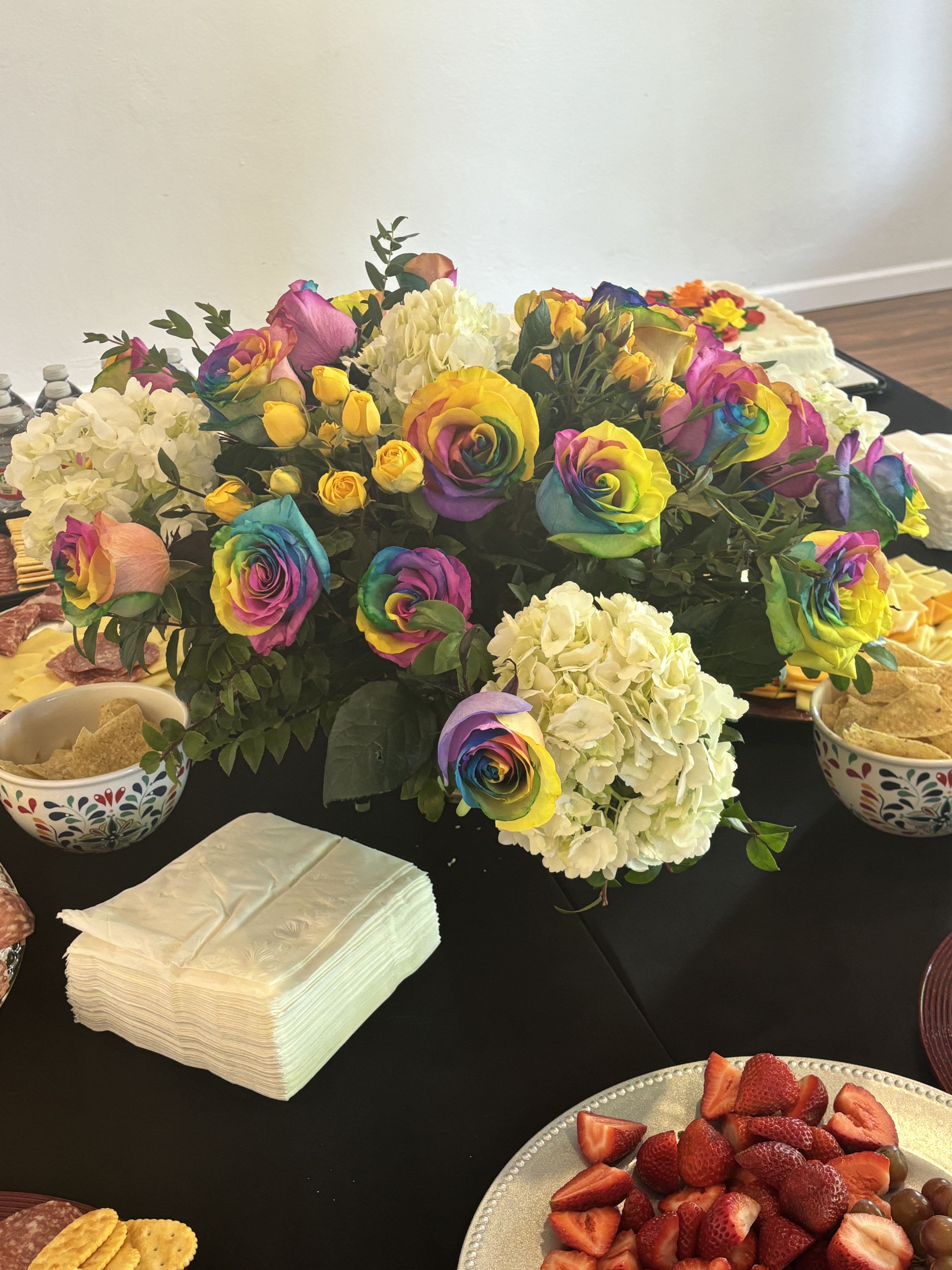 Rainbow roses and white hydrangeas arranged on a table.