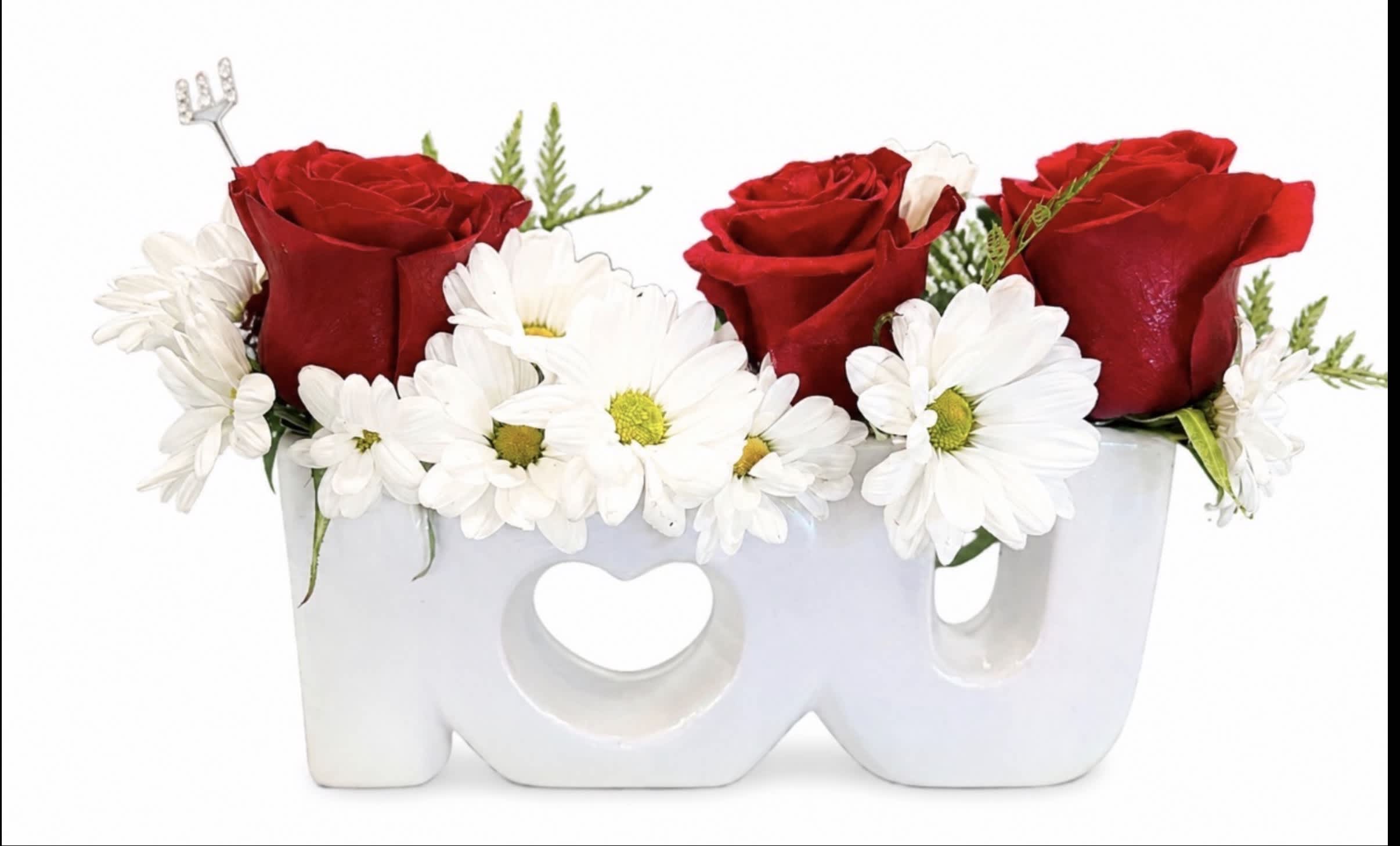 Red roses and white daisies arranged in a white LOVE container