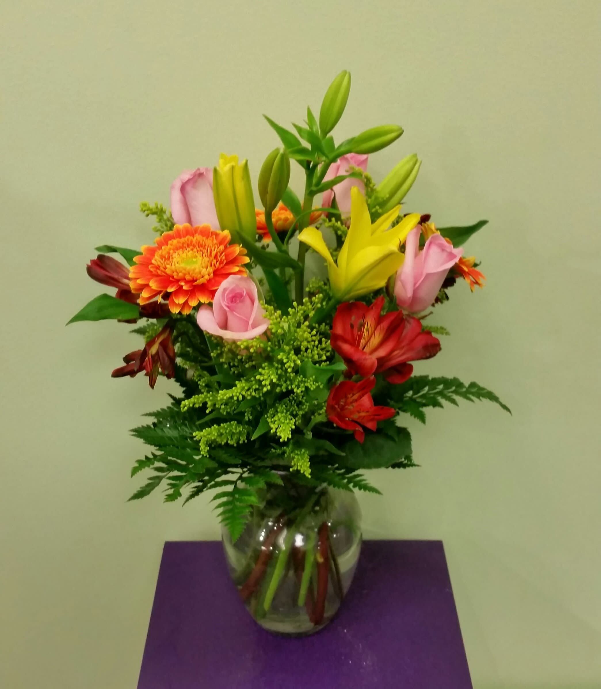 Mixed bouquet of lilies, roses, and gerbera daisies in a glass vase